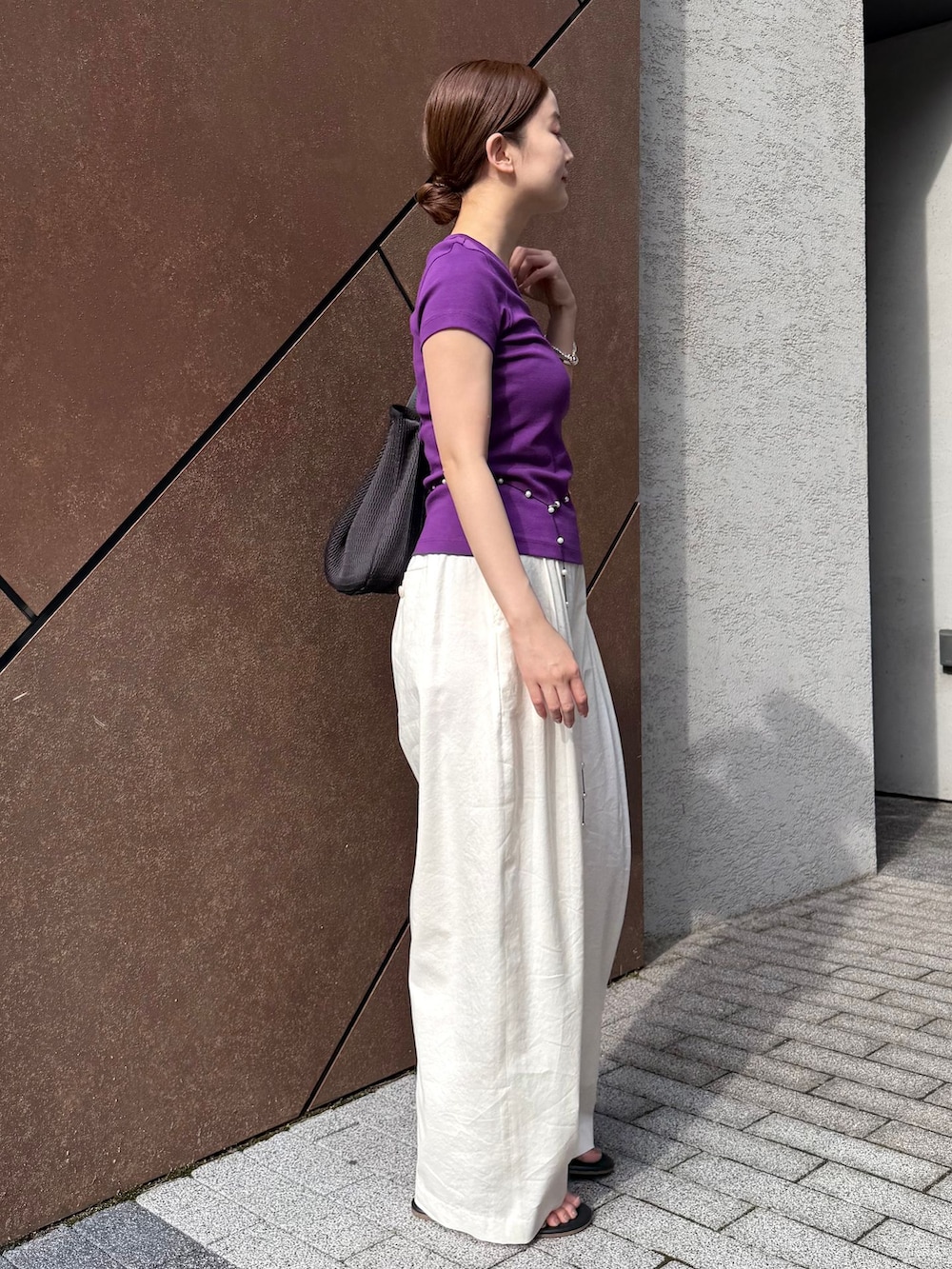 ホワイト系のスラックス、パープル系のTシャツ/カットソー、ブラック系のサンダルを着用したレディースの夏コーディネートの3枚目の写真