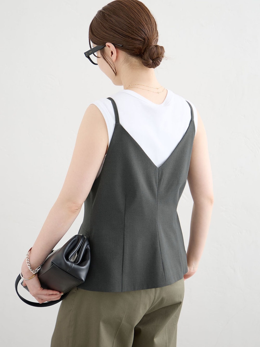 グレー系のベスト、グリーン系のチノパンツ、シルバー系のサンダルを着用したレディースの夏コーディネートの5枚目の写真