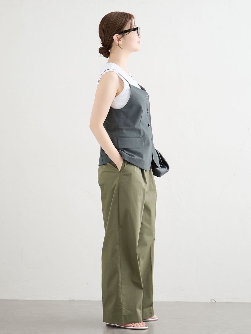 グレー系のベスト、グリーン系のチノパンツ、シルバー系のサンダルを着用したレディースの夏コーディネートの2枚目の写真