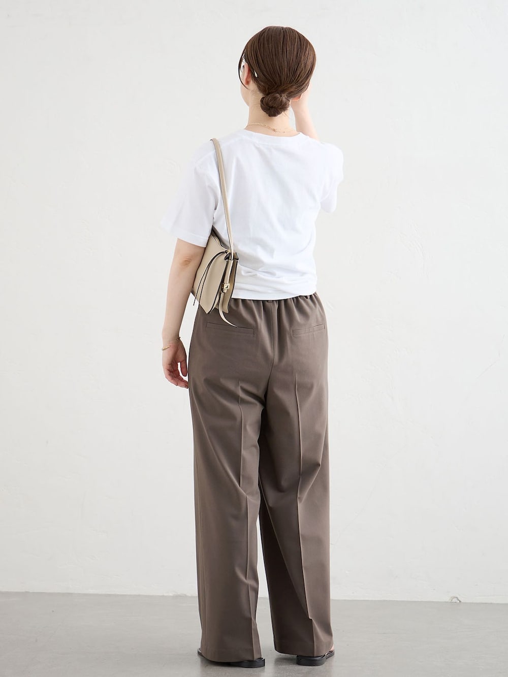 ブラウン系のスラックス、ホワイト系のTシャツ/カットソー、ブラック系のサンダルを着用したレディースの夏コーディネートの3枚目の写真