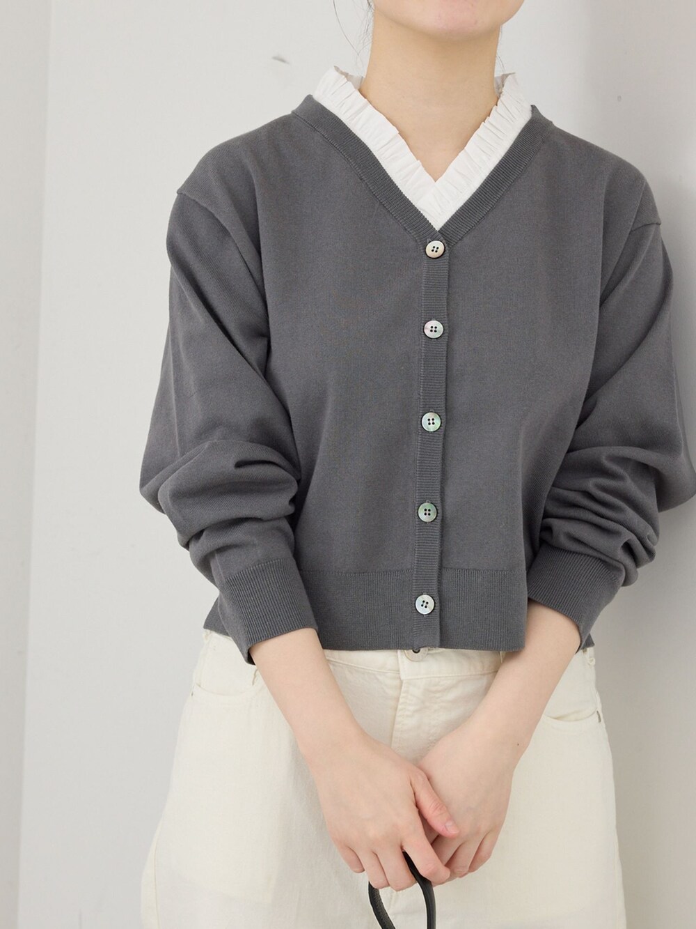 ホワイト系のデニムパンツ、グレー系のカーディガン/ボレロ、ブラック系のハンドバッグを着用したレディースの春コーディネートの3枚目の写真