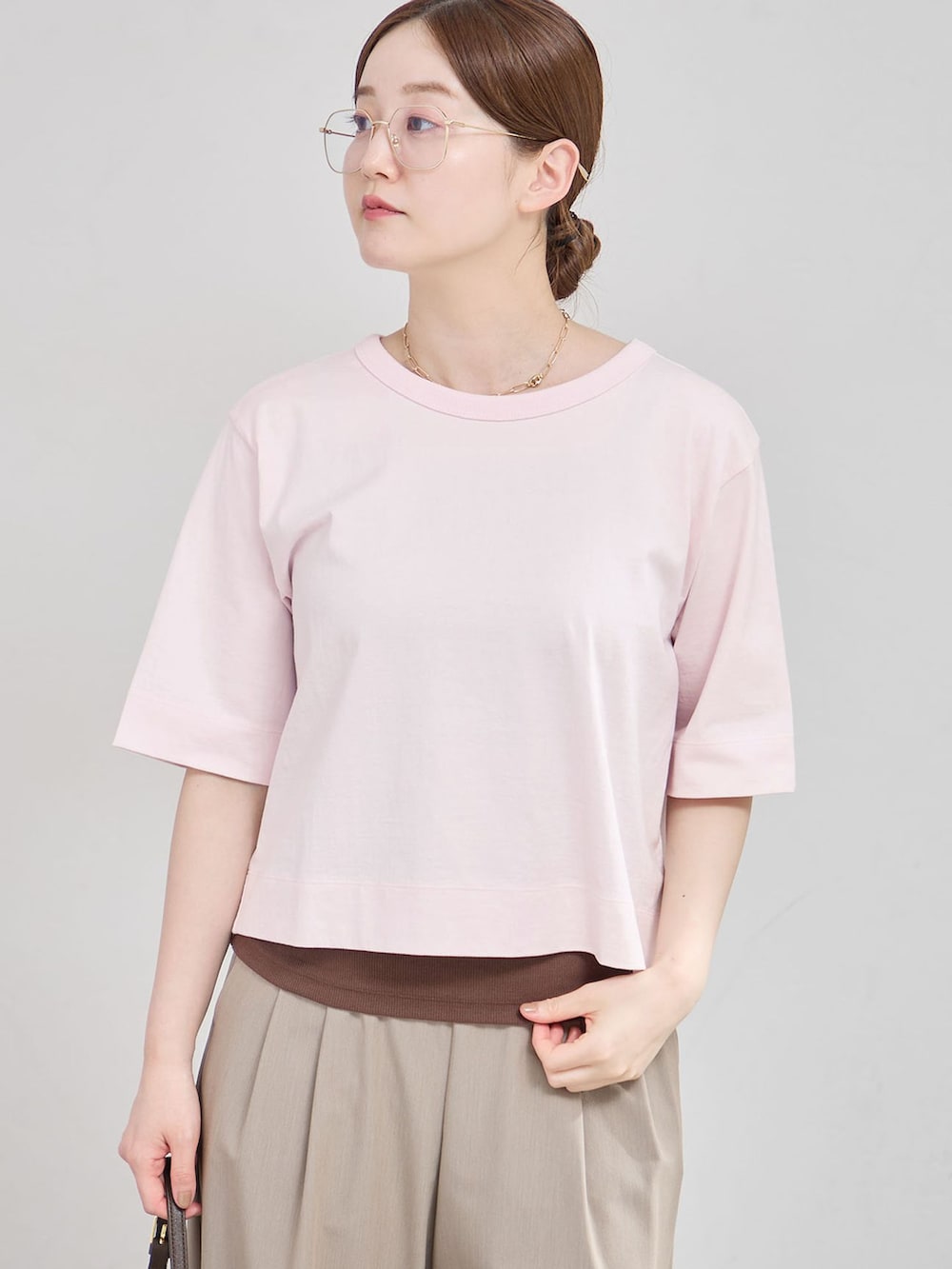 ベージュ系のスラックス、ピンク系のTシャツ/カットソー、ブラウン系のサンダルを着用したレディースの夏コーディネートの3枚目の写真