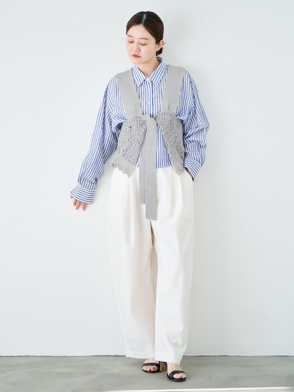 ホワイト系のスラックス、ブルー系のシャツ/ブラウス、グレー系のニット/セーターを着用したレディースの春コーディネートの3枚目の写真