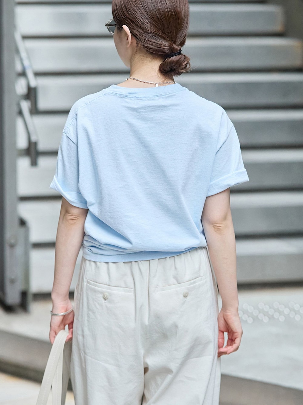 ホワイト系のスラックス、ブルー系のTシャツ/カットソー、ブラウン系のトートバッグを着用したレディースの秋コーディネートの5枚目の写真