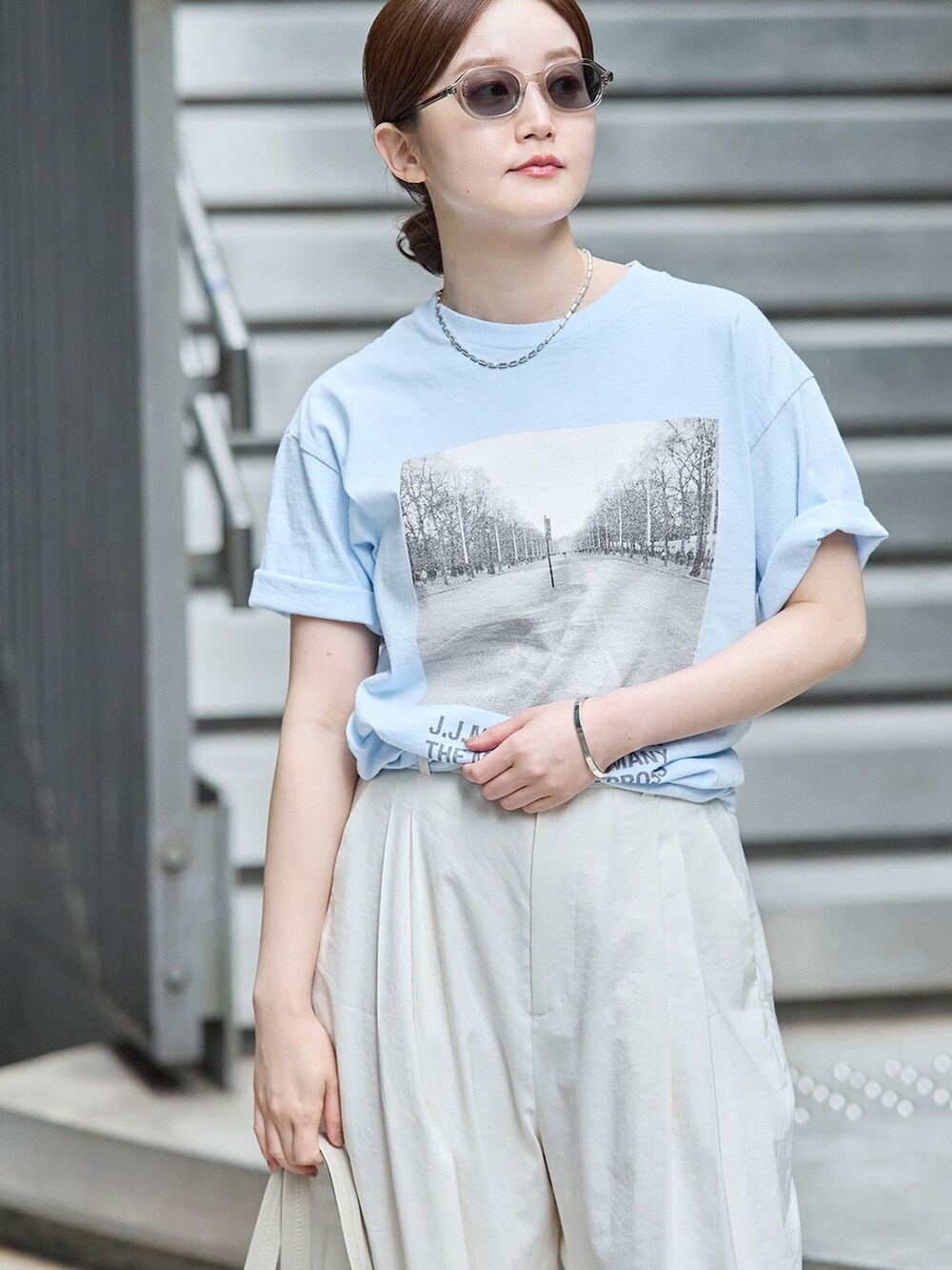 ホワイト系のスラックス、ブルー系のTシャツ/カットソー、ブラウン系のトートバッグを着用したレディースの秋コーディネートの4枚目の写真