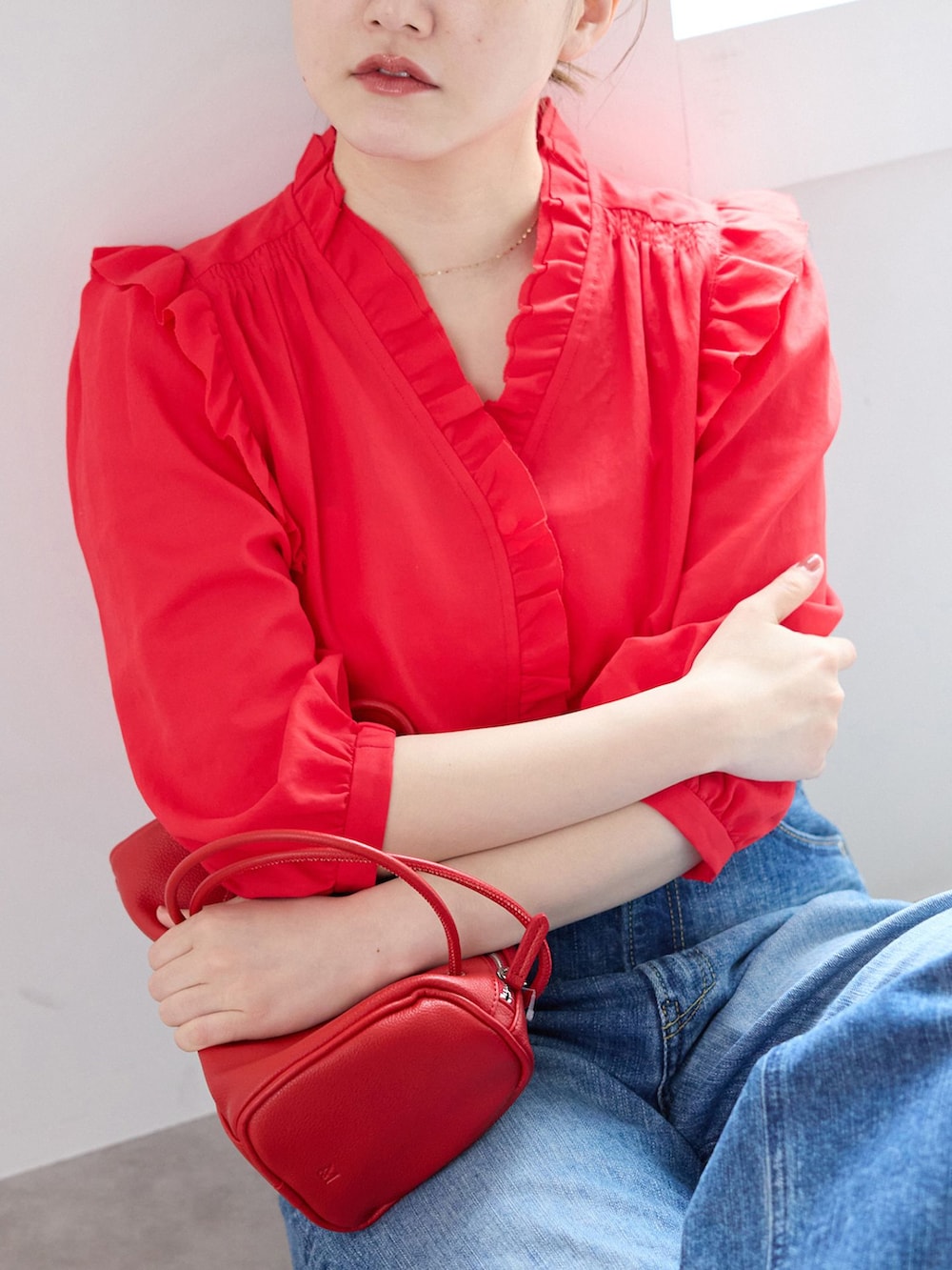 ブルー系のデニムパンツ、レッド系のシャツ/ブラウス、レッド系のショルダーバッグを着用したレディースの春コーディネートの5枚目の写真