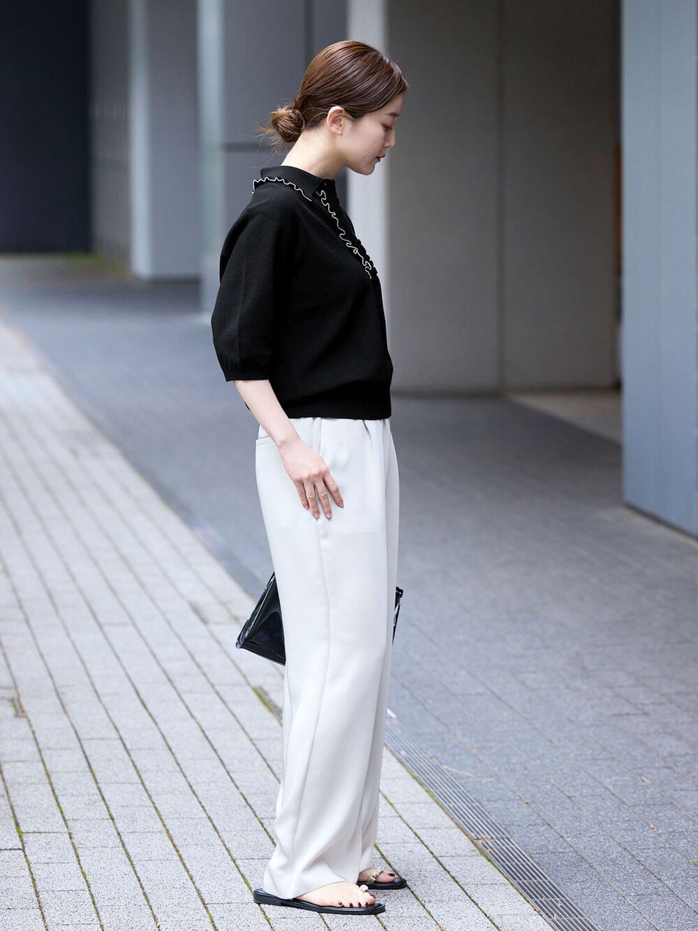 ベージュ系のその他パンツ、ブラック系のニット/セーター、ブラック系のサンダルを着用したレディースの春コーディネートの2枚目の写真
