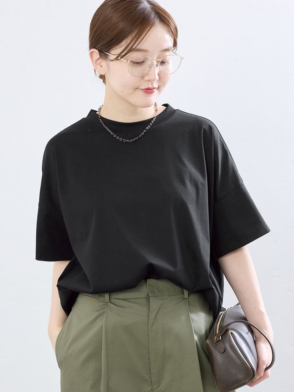 グリーン系のチノパンツ、ブラック系のTシャツ/カットソー、ゴールド系のサンダルを着用したレディースの夏コーディネートの4枚目の写真