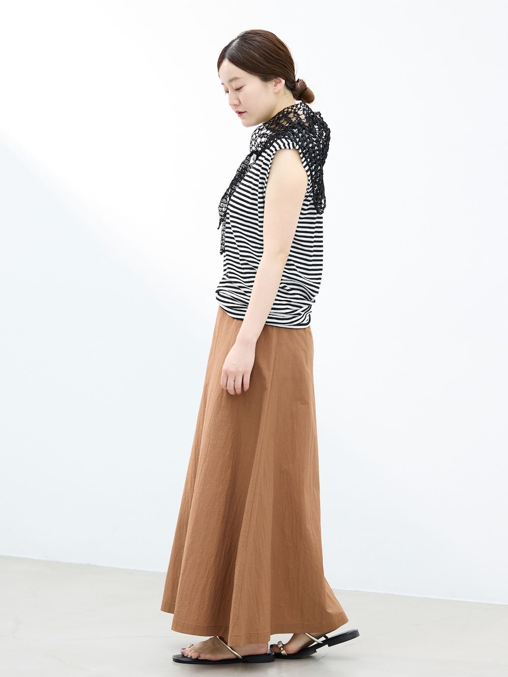 イエロー系のスカート、ブラック系のTシャツ/カットソー、ブラック系のサンダルを着用したレディースの春コーディネートの2枚目の写真