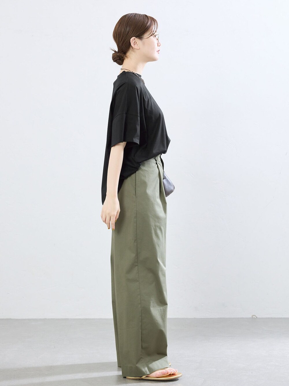グリーン系のチノパンツ、ブラック系のTシャツ/カットソー、ゴールド系のサンダルを着用したレディースの夏コーディネートの2枚目の写真