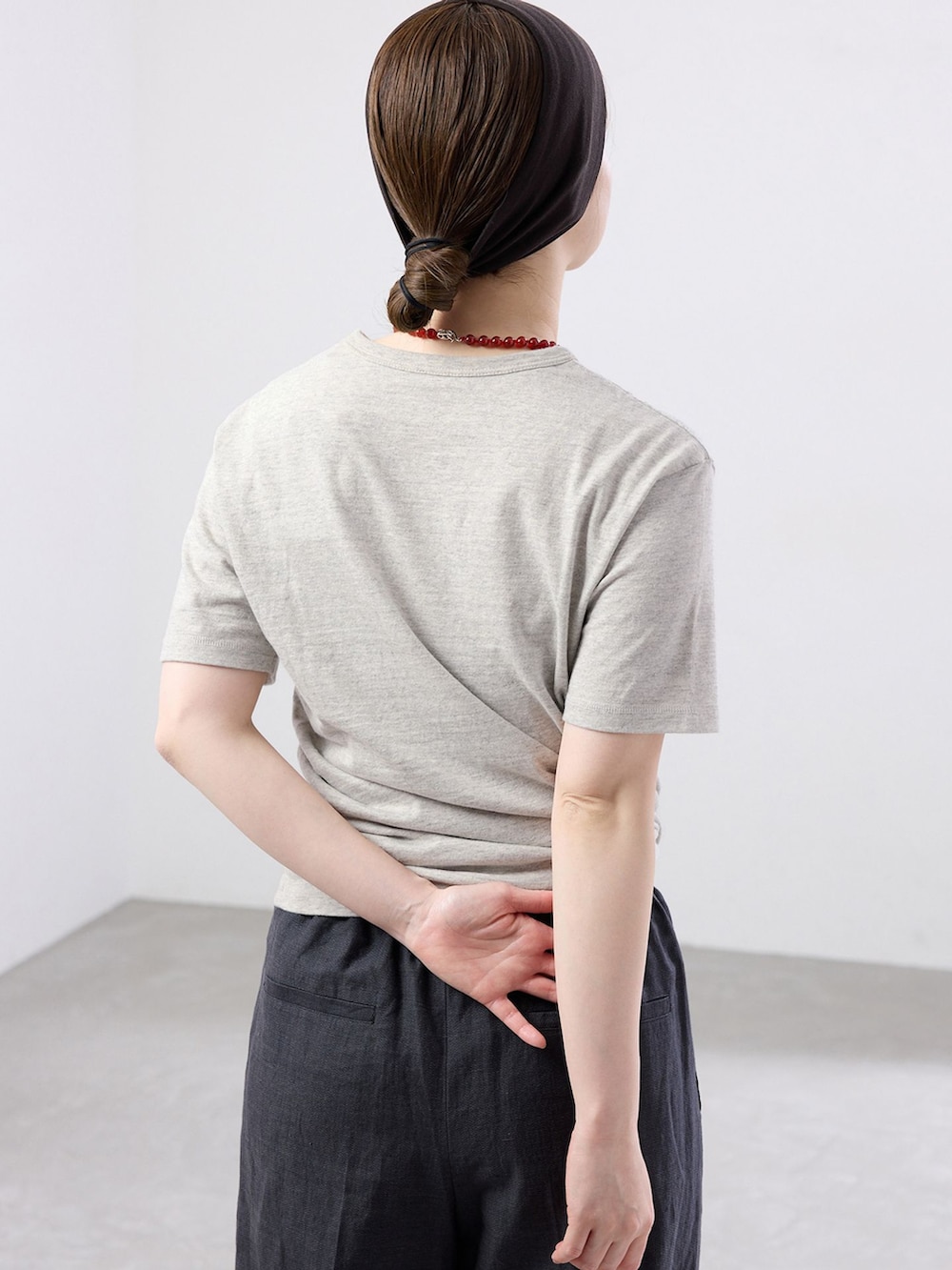 ブラック系のスラックス、グレー系のTシャツ/カットソー、ブラック系のサンダルを着用したレディースの春コーディネートの4枚目の写真