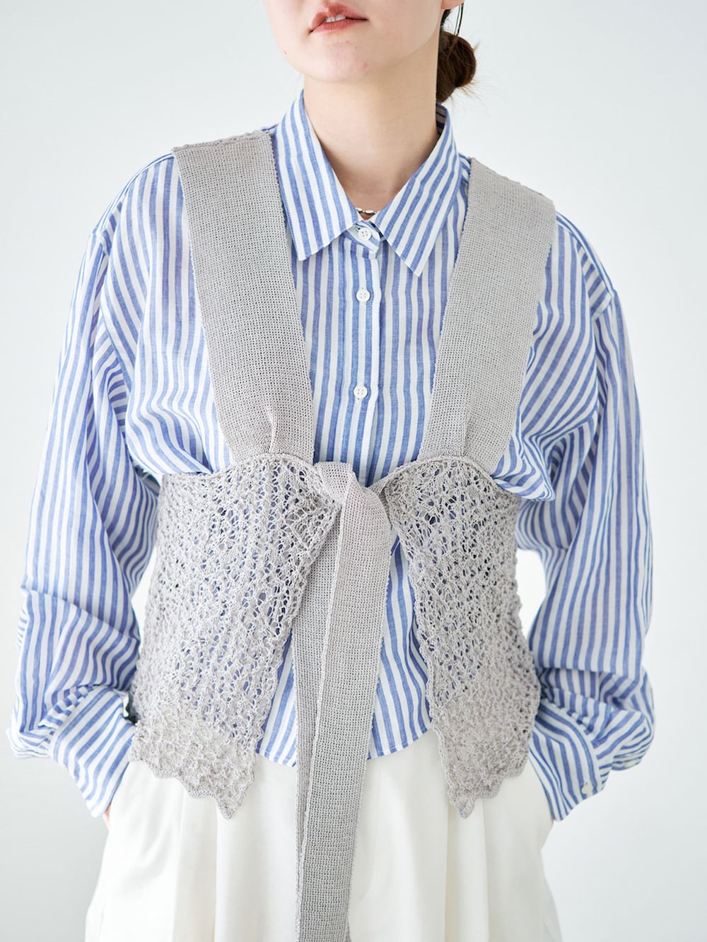 ホワイト系のスラックス、ブルー系のシャツ/ブラウス、グレー系のニット/セーターを着用したレディースの春コーディネートの4枚目の写真