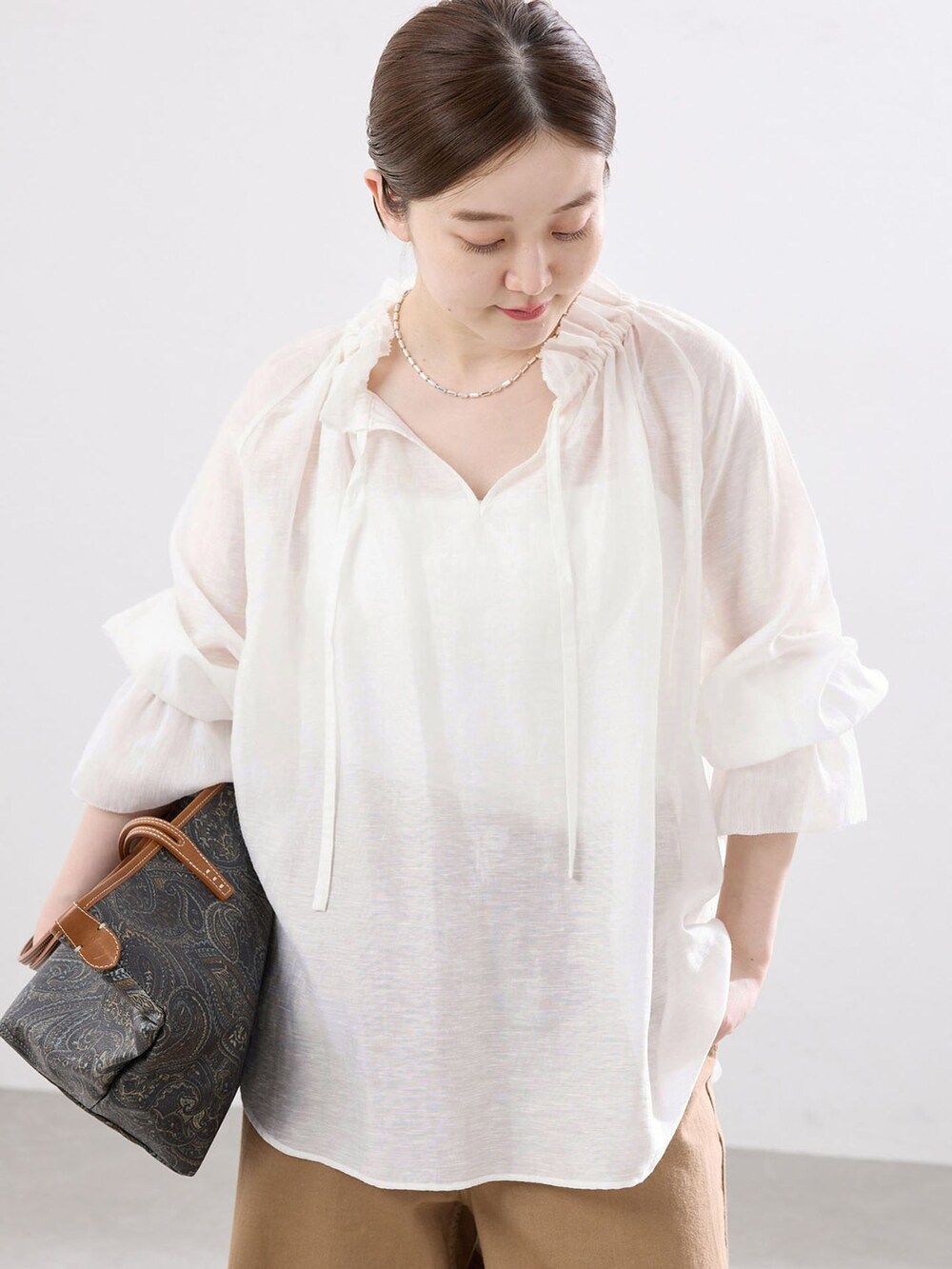 イエロー系のチノパンツ、ホワイト系のシャツ/ブラウス、ブラウン系のサンダルを着用したレディースの春コーディネートの4枚目の写真