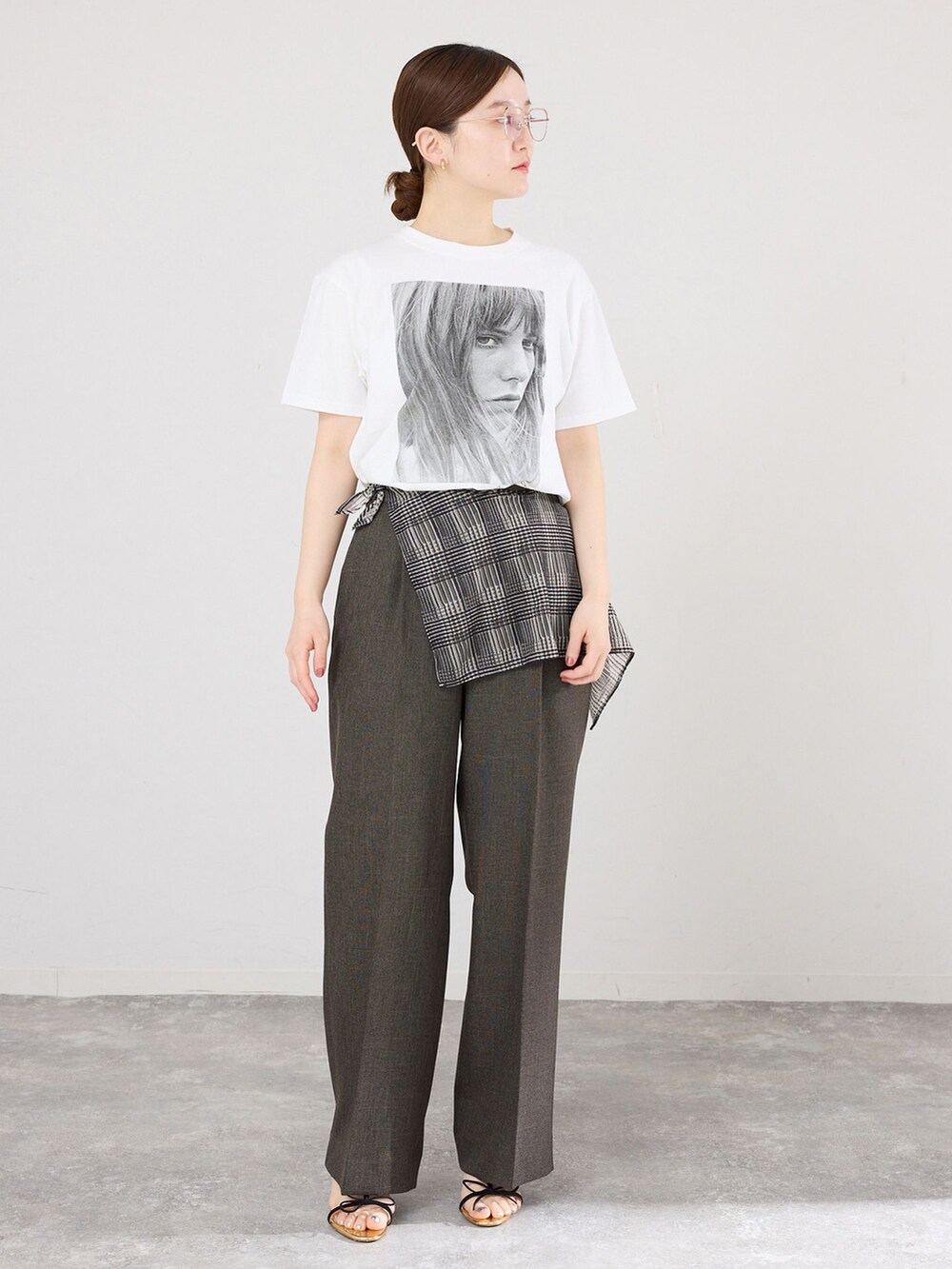 ブラウン系のスラックス、ホワイト系のTシャツ/カットソー、ブラック系のサンダルを着用したレディースの春コーディネートの3枚目の写真