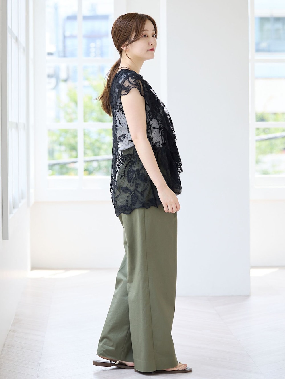 グリーン系のチノパンツ、ブラック系のベスト、ブラウン系のサンダルを着用したレディースの夏コーディネートの2枚目の写真