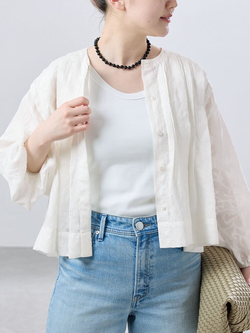 ブルー系のデニムパンツ、ベージュ系のトートバッグ、ブラック系のネックレスを着用したレディースの夏コーディネートの4枚目の写真