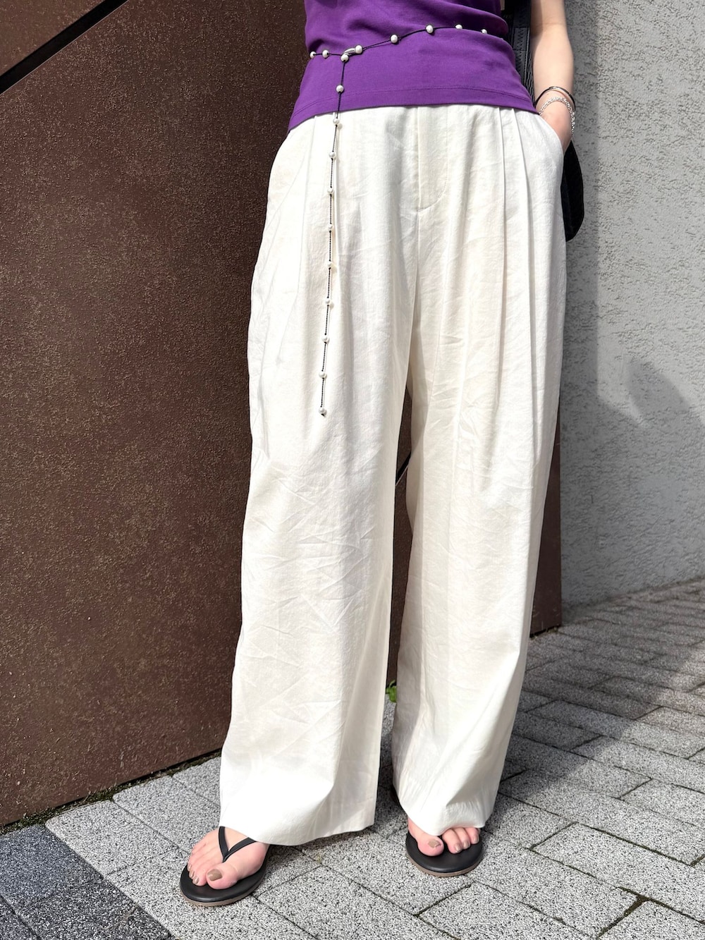 ホワイト系のスラックス、パープル系のTシャツ/カットソー、ブラック系のサンダルを着用したレディースの夏コーディネートの4枚目の写真