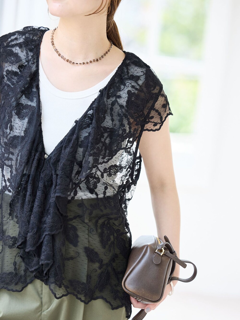 グリーン系のチノパンツ、ブラック系のベスト、ブラウン系のサンダルを着用したレディースの夏コーディネートの6枚目の写真