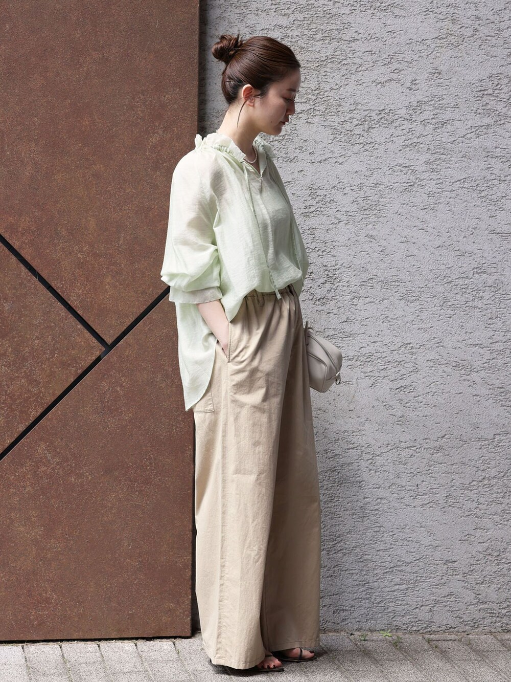 ベージュ系のその他パンツ、グリーン系のシャツ/ブラウス、ホワイト系のショルダーバッグを着用したレディースの春コーディネートの2枚目の写真