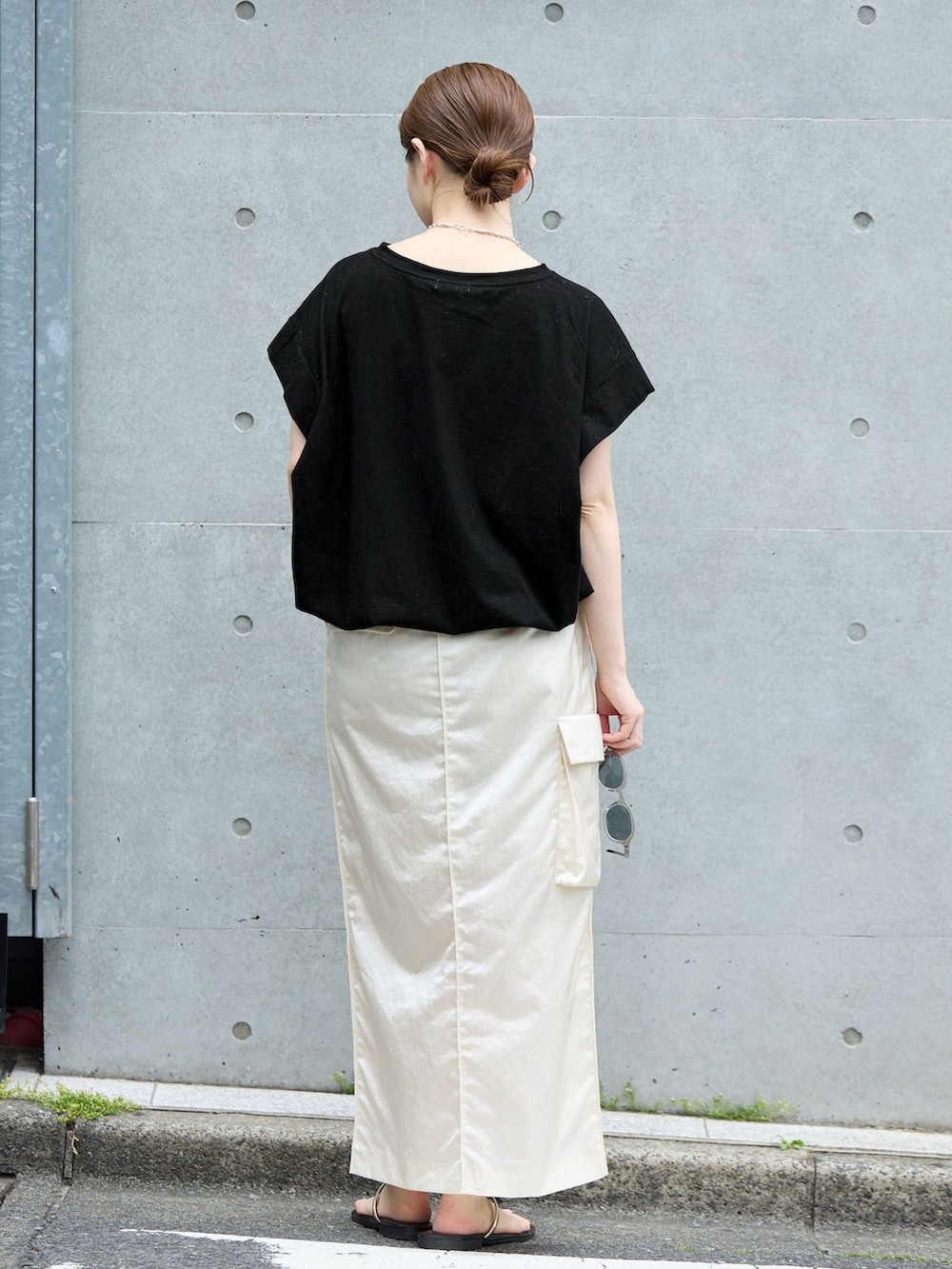 ホワイト系のスカート、ブラック系のTシャツ/カットソー、ブラック系のサンダルを着用したレディースの夏コーディネートの3枚目の写真