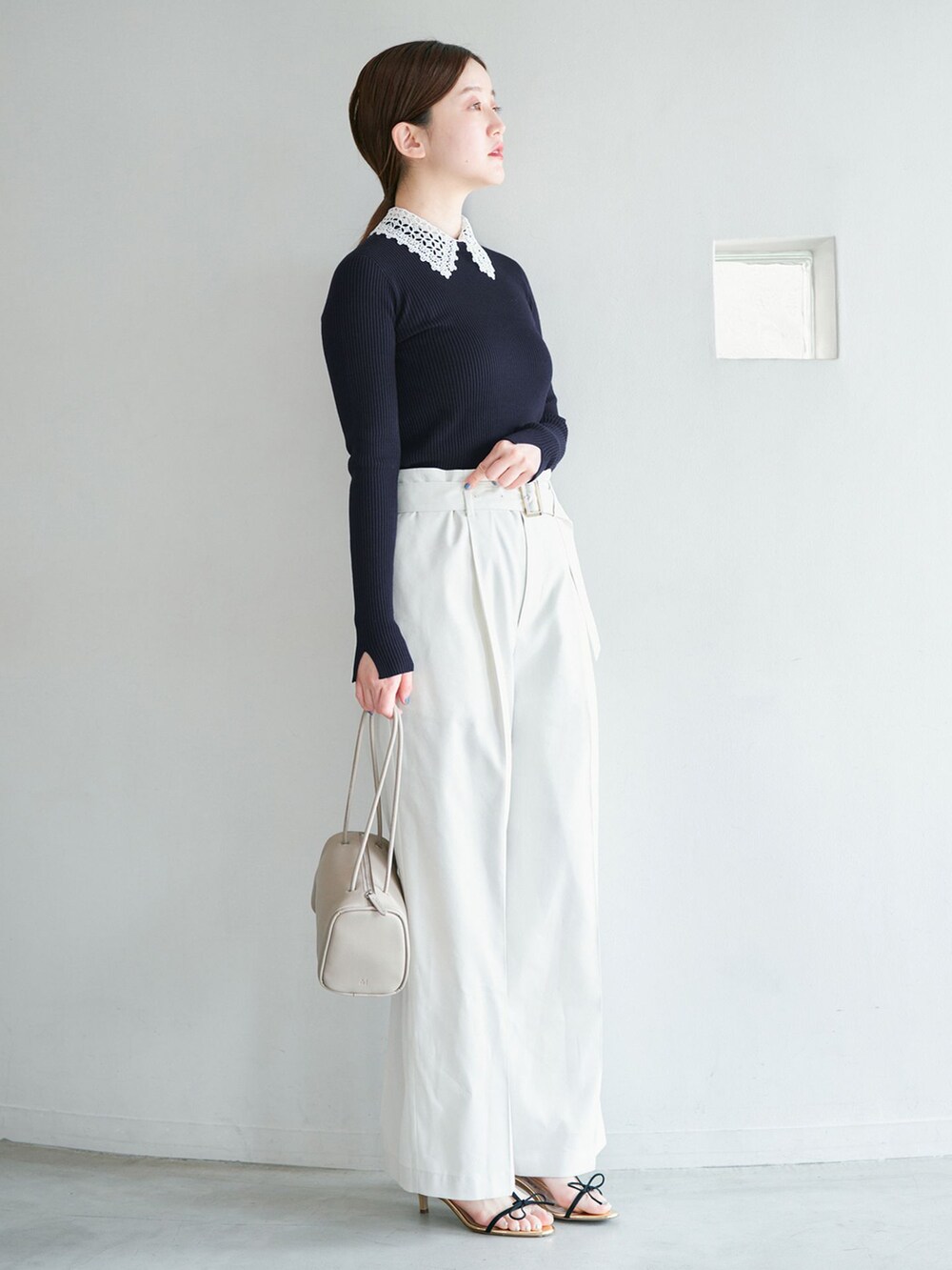 ホワイト系のチノパンツ、ブルー系のニット/セーター、イエロー系のショルダーバッグを着用したレディースの冬コーディネートの2枚目の写真