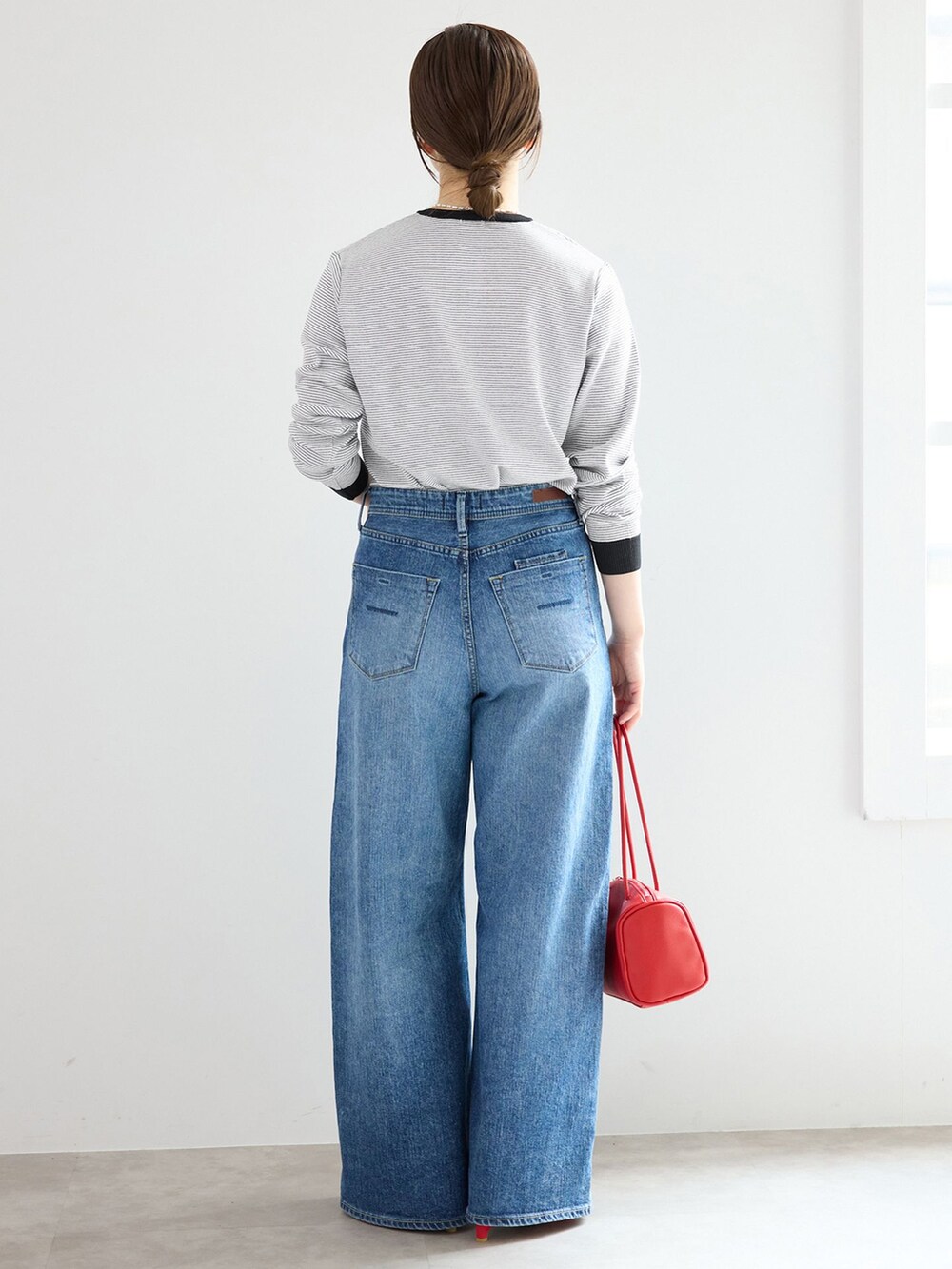 ブルー系のデニムパンツ、レッド系のショルダーバッグを着用したレディースの春コーディネートの3枚目の写真