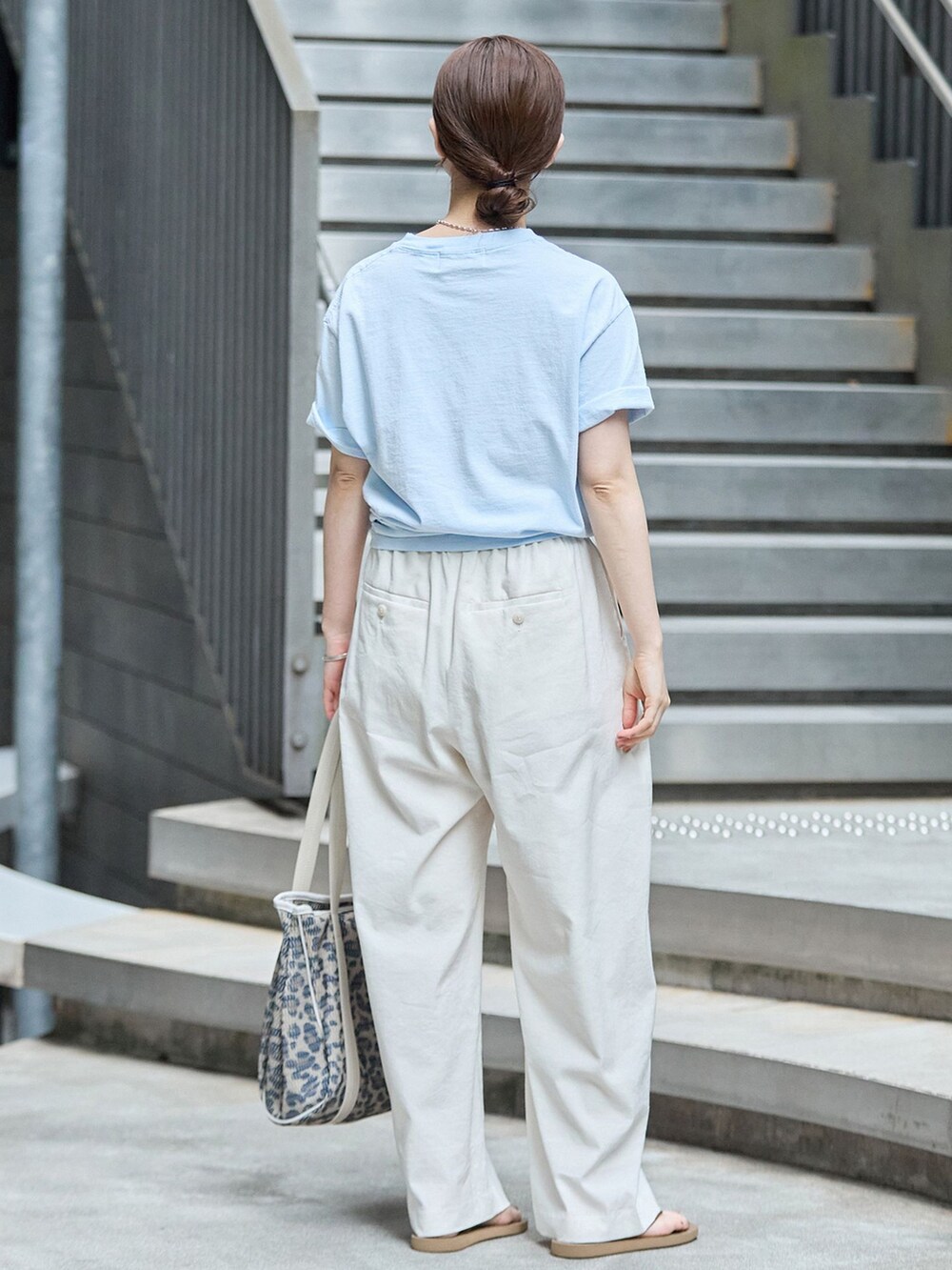 ホワイト系のスラックス、ブルー系のTシャツ/カットソー、ブラウン系のトートバッグを着用したレディースの秋コーディネートの3枚目の写真