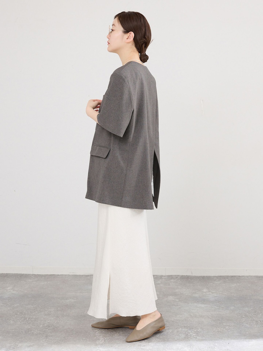 グレー系のその他シューズ、ブラウン系のノーカラージャケット、ホワイト系のキャミソールを着用したレディースの春コーディネートの2枚目の写真