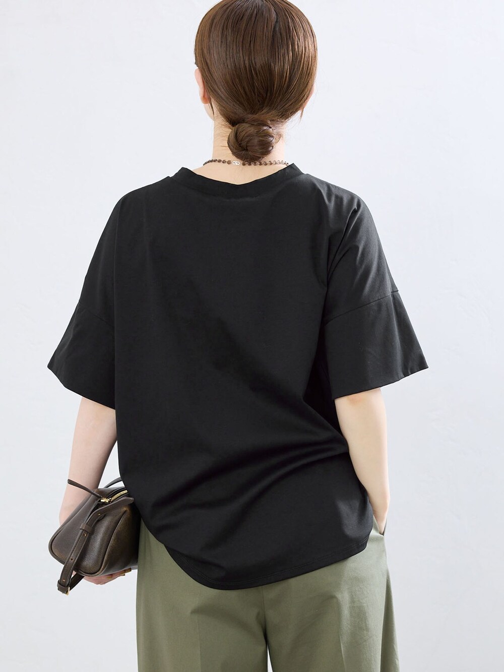 グリーン系のチノパンツ、ブラック系のTシャツ/カットソー、ゴールド系のサンダルを着用したレディースの夏コーディネートの5枚目の写真