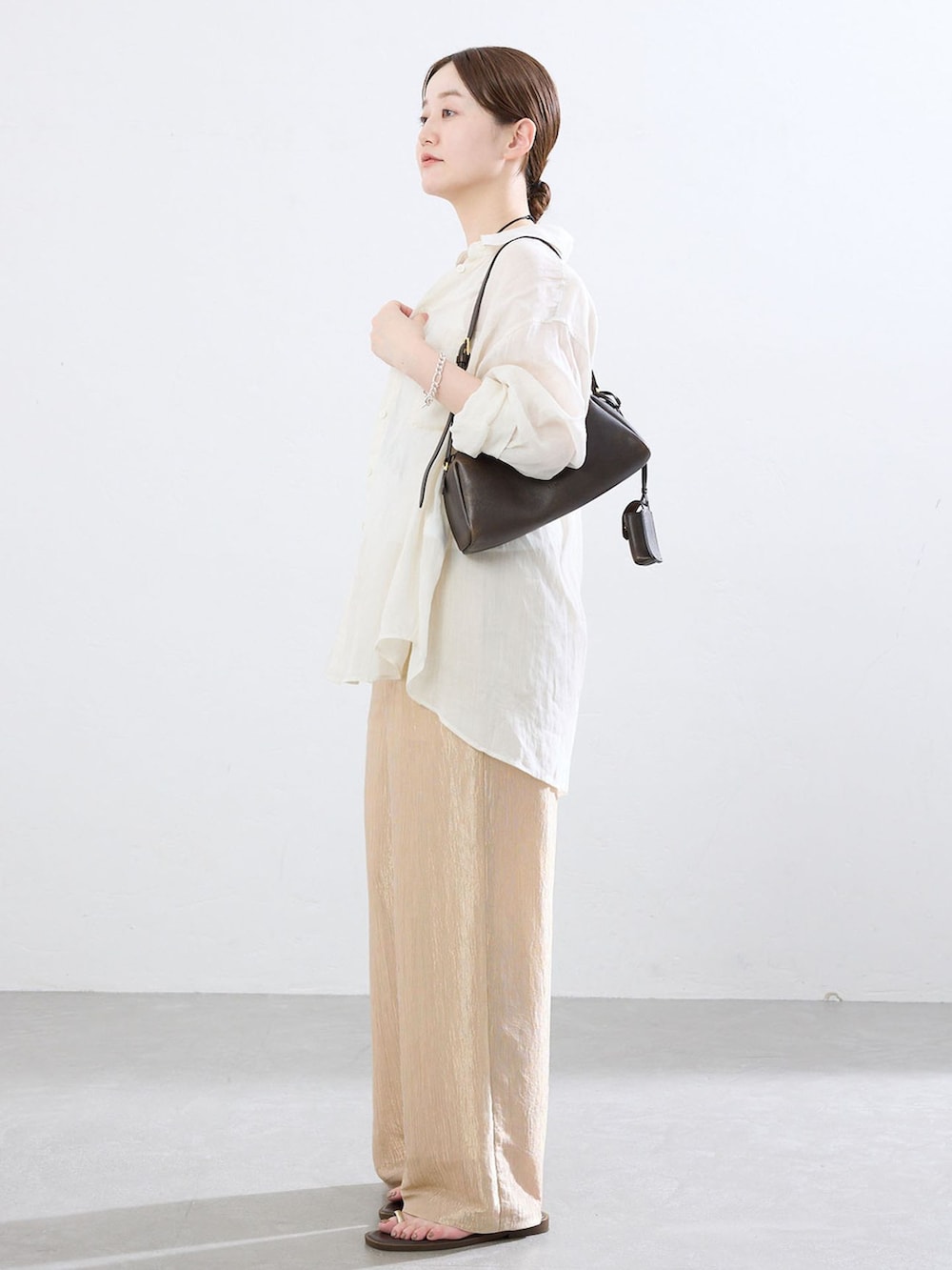 ゴールド系のその他パンツ、ホワイト系のシャツ/ブラウス、ブラウン系のサンダルを着用したレディースの夏コーディネートの2枚目の写真