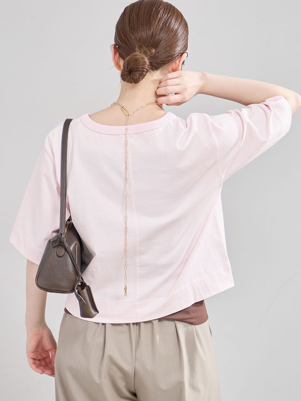 ベージュ系のスラックス、ピンク系のTシャツ/カットソー、ブラウン系のサンダルを着用したレディースの夏コーディネートの4枚目の写真