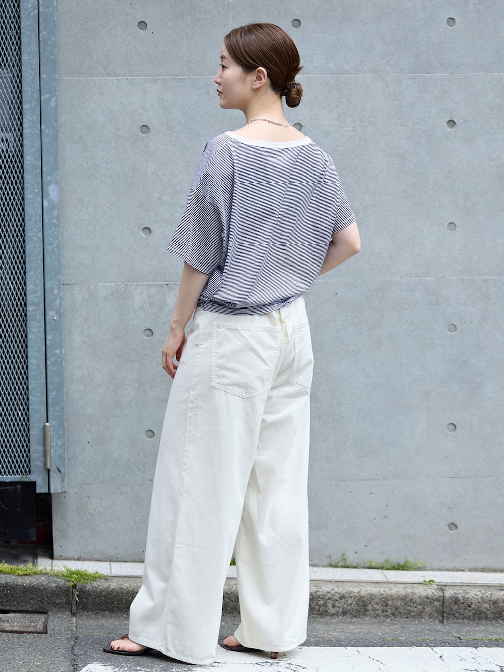ホワイト系のチノパンツ、ブルー系のTシャツ/カットソー、ブラウン系のサンダルを着用したレディースの春コーディネートの2枚目の写真