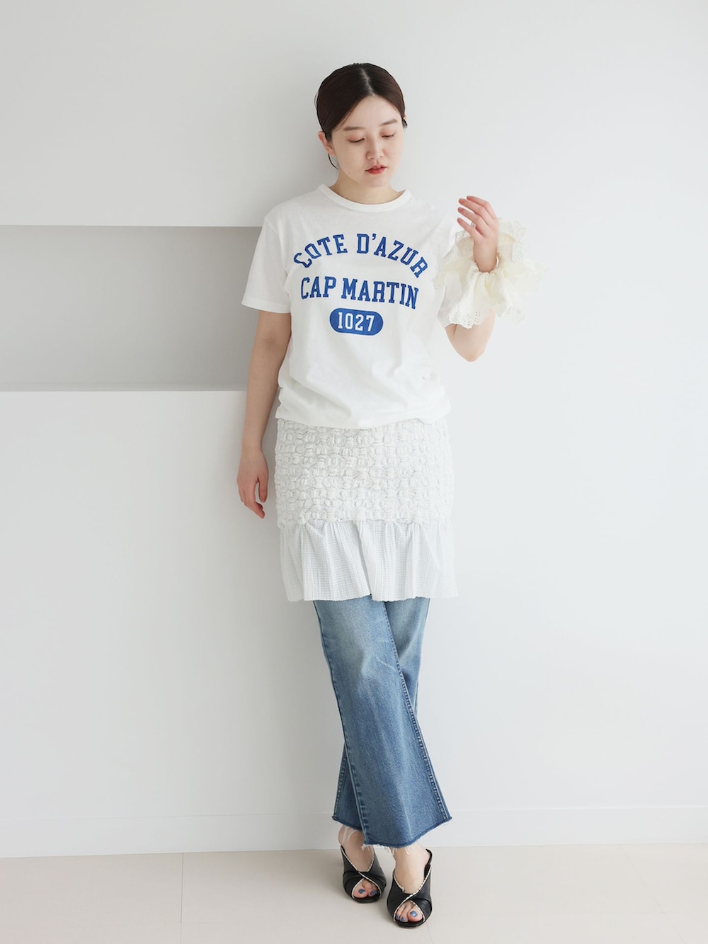 ブルー系のデニムパンツ、ホワイト系のスカート、ホワイト系のTシャツ/カットソーを着用したレディースの春コーディネートの2枚目の写真
