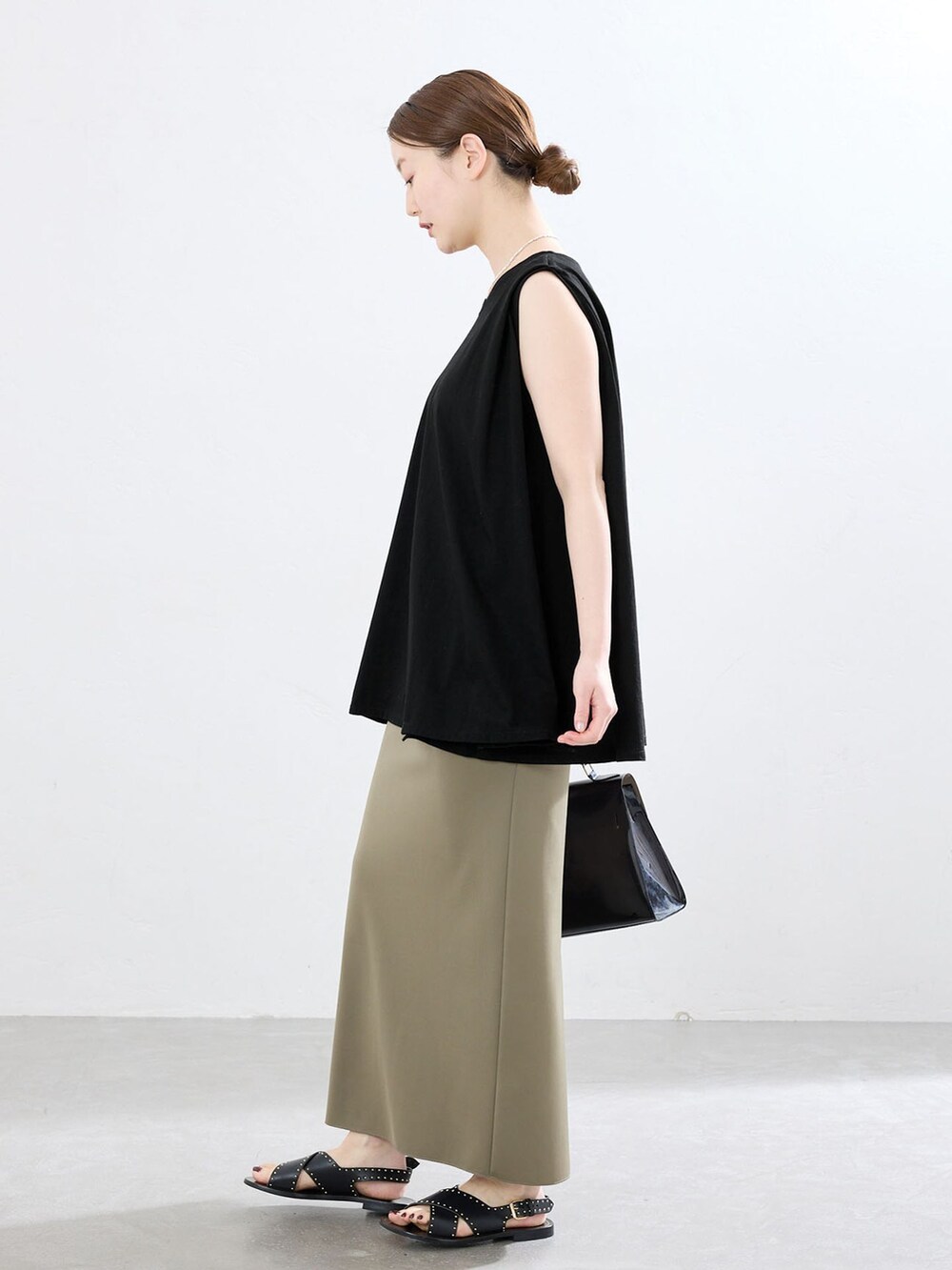 グリーン系のスカート、ブラック系のTシャツ/カットソー、ブラック系のサンダルを着用したレディースの夏コーディネートの2枚目の写真