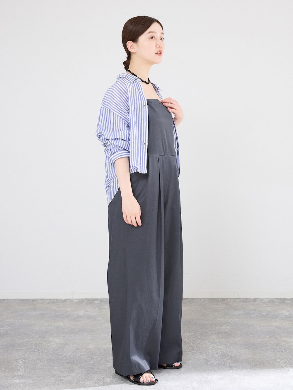 グレー系のサロペット/オーバーオール、ブルー系のシャツ/ブラウス、ブラック系のネックレスを着用したレディースの春コーディネートの2枚目の写真