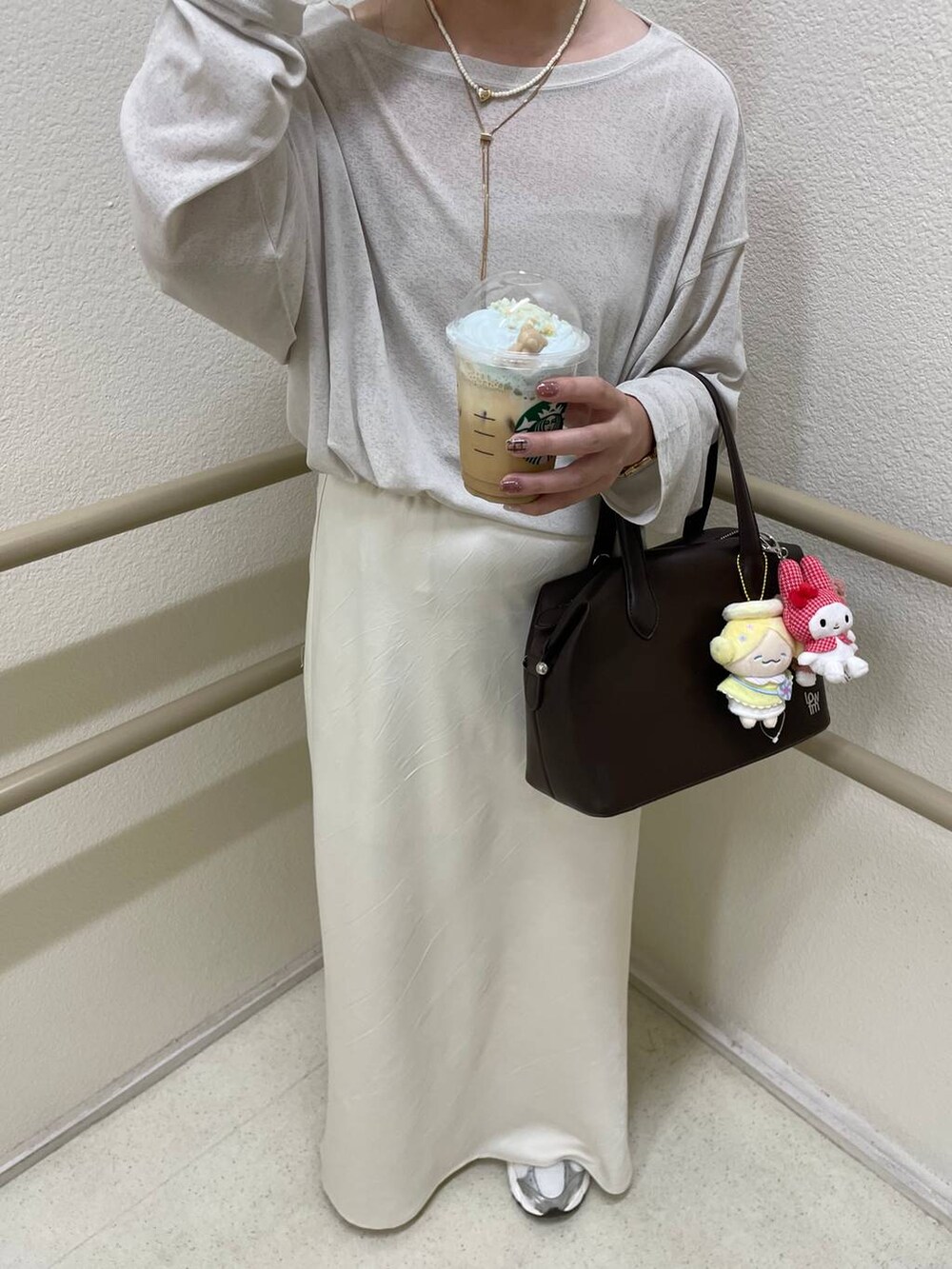 ブラウン系のショルダーバッグ、ホワイト系のスカート、ベージュ系のTシャツ/カットソーを着用したレディースの秋コーディネートの2枚目の写真