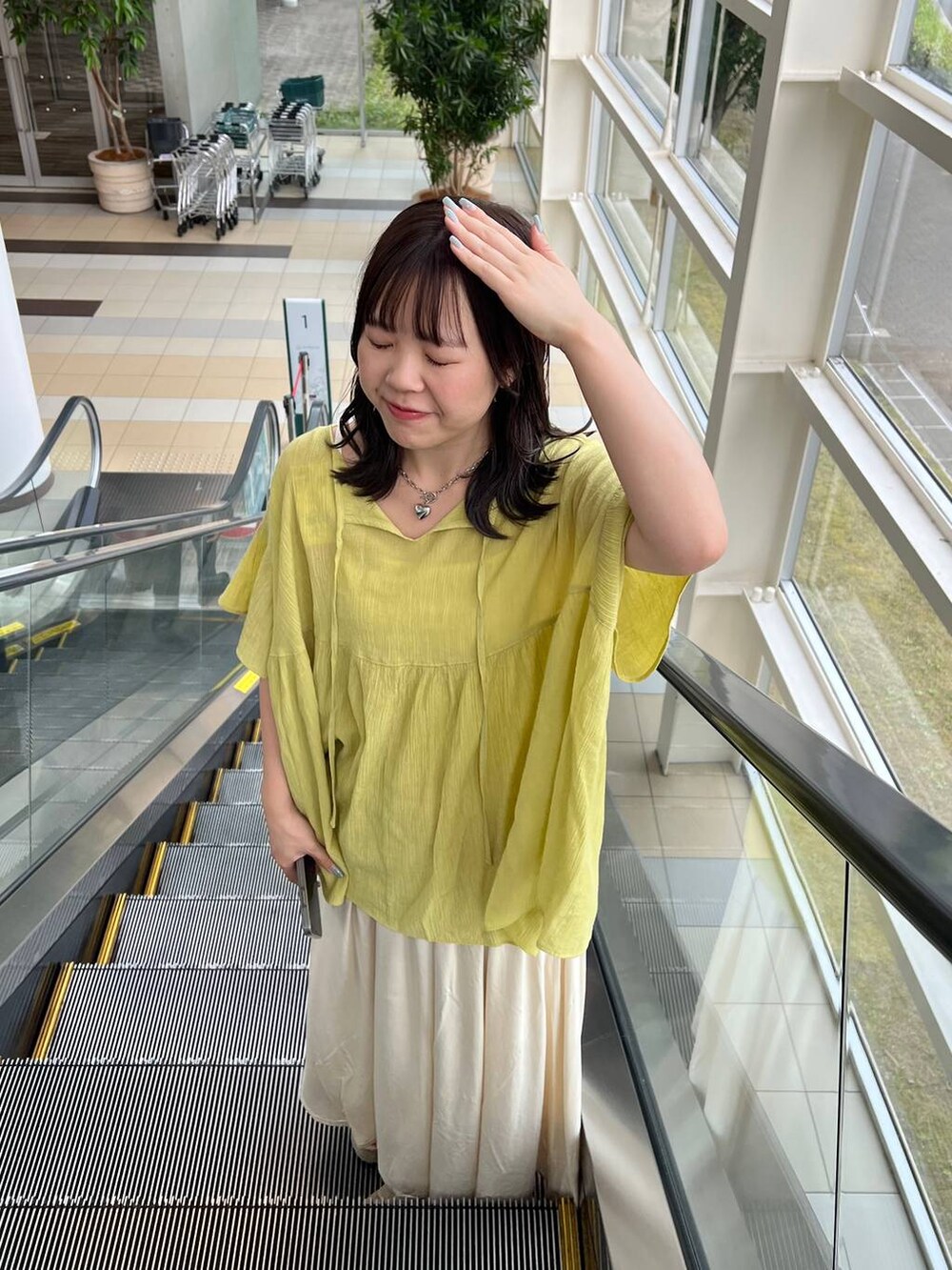 ホワイト系のサンダル、ホワイト系のショルダーバッグ、グリーン系のシャツ/ブラウスを着用したレディースの夏コーディネートの2枚目の写真