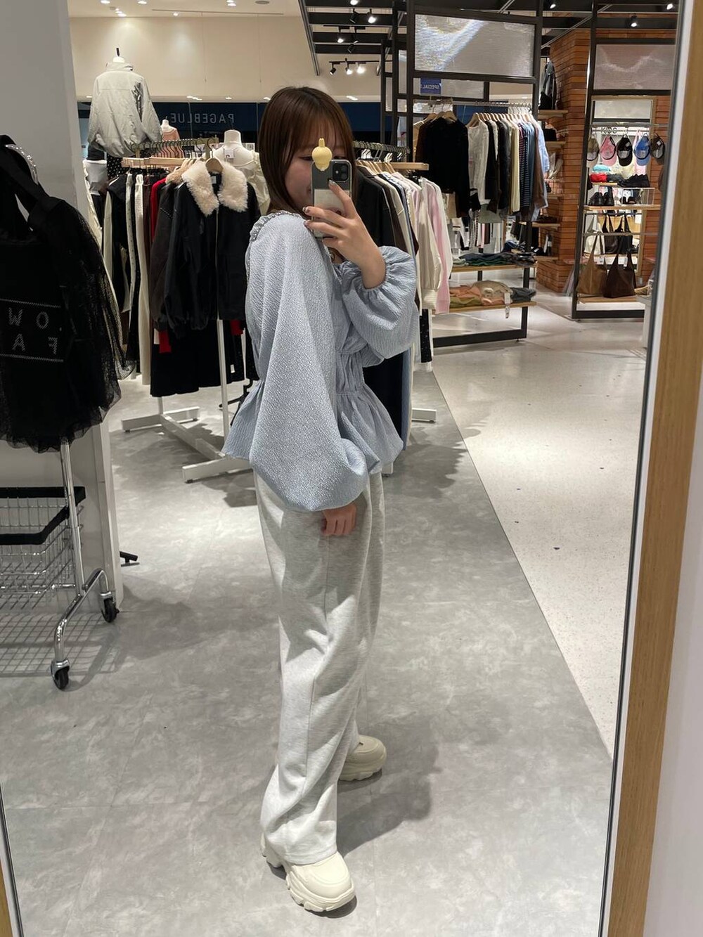 シルバー系のショルダーバッグ、グレー系のスウェットパンツ、ブルー系のTシャツ/カットソーを着用したレディースの冬コーディネートの3枚目の写真