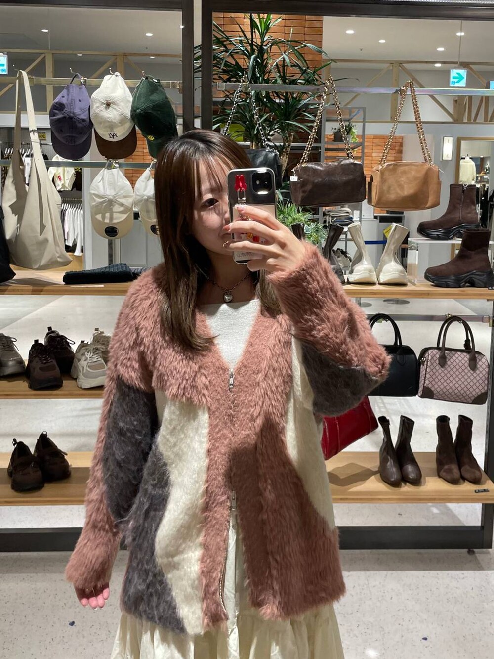 ブラック系のブーツ、ピンク系のカーディガン/ボレロ、ホワイト系のスカートを着用したレディースの秋コーディネートの2枚目の写真