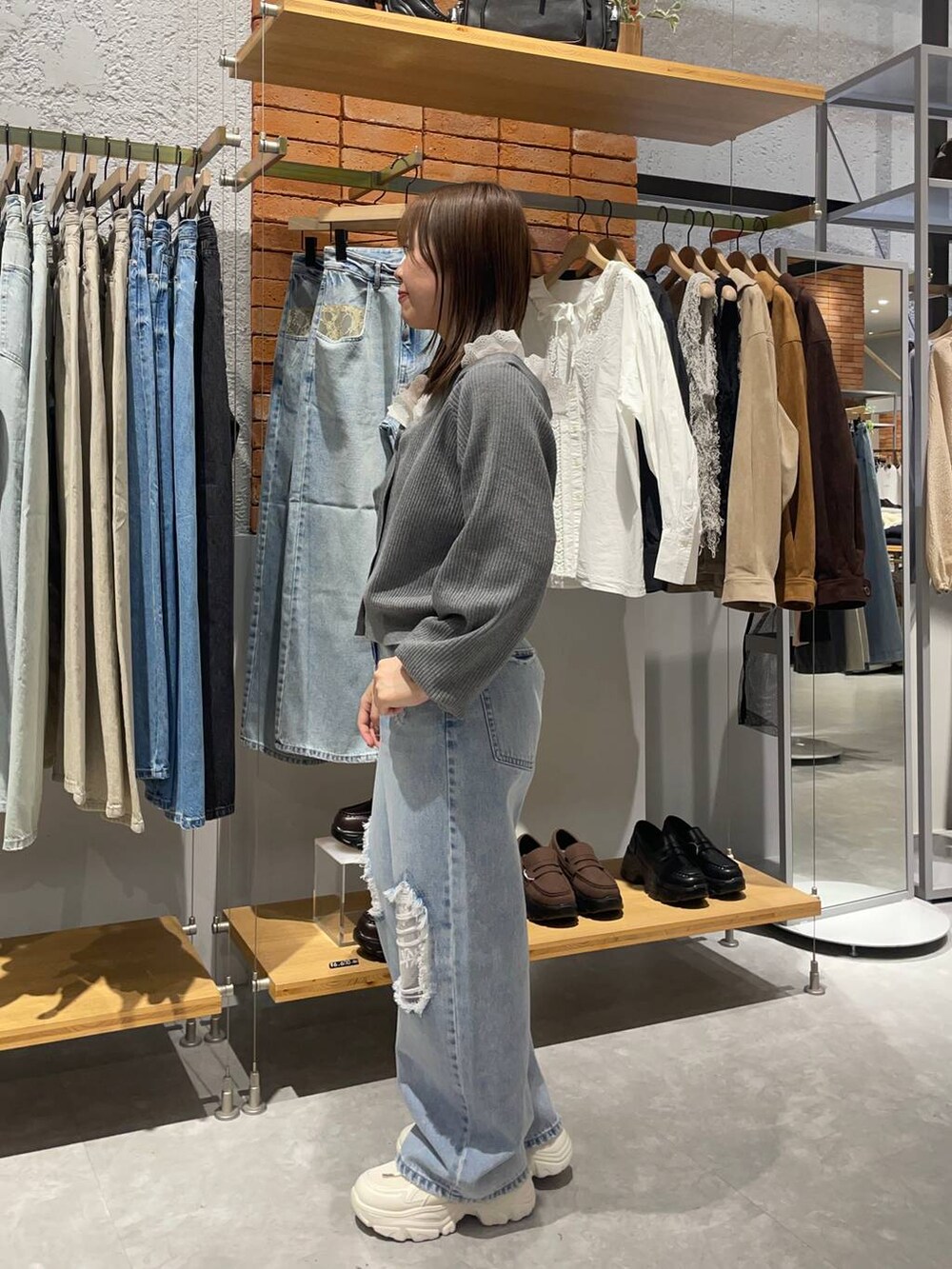 ブルー系のデニムパンツ、グレー系のカーディガン/ボレロ、ホワイト系のスニーカーを着用したレディースの冬コーディネートの3枚目の写真