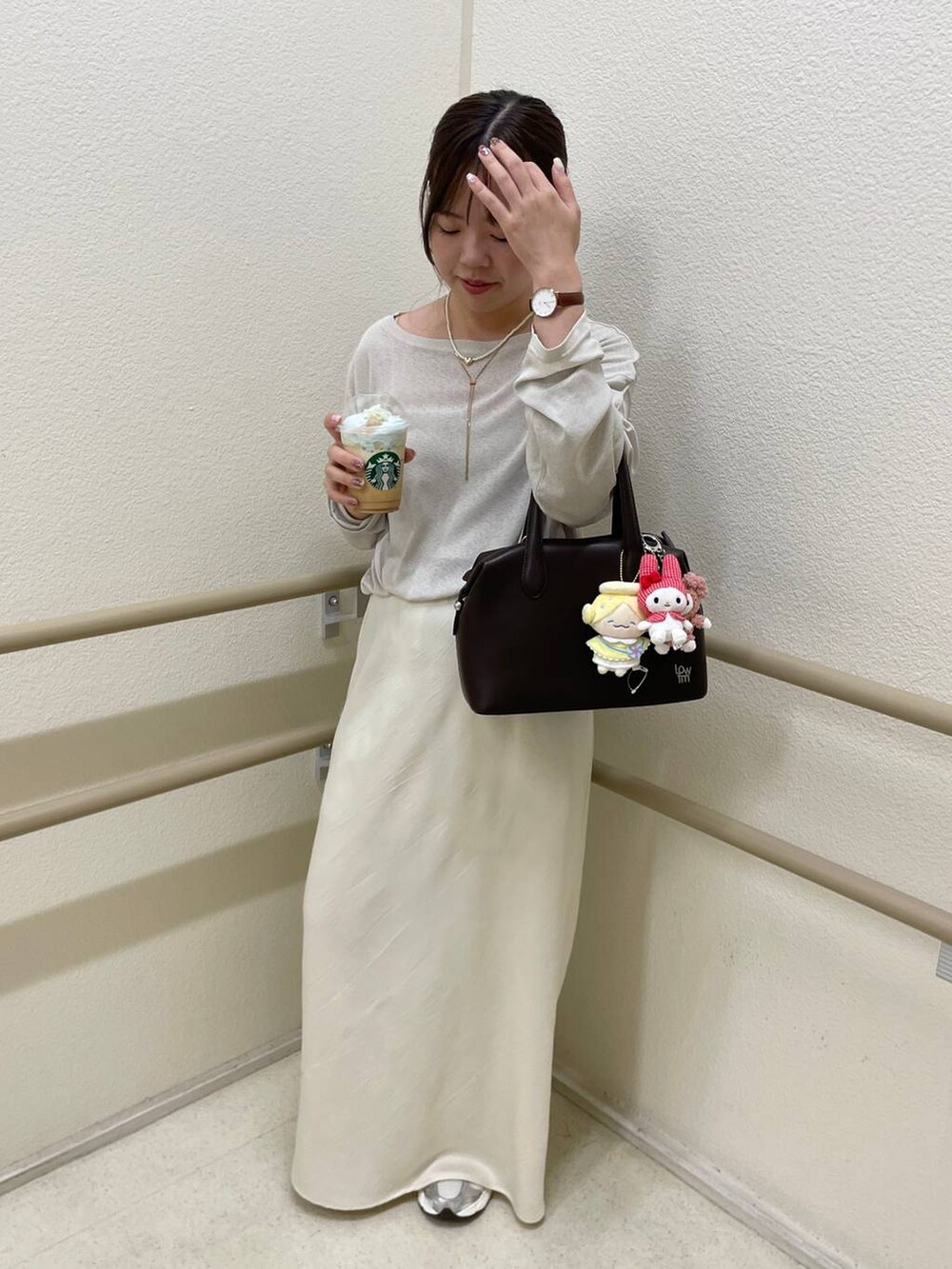 ブラウン系のショルダーバッグ、ホワイト系のスカート、ベージュ系のTシャツ/カットソーを着用したレディースの秋コーディネートの3枚目の写真