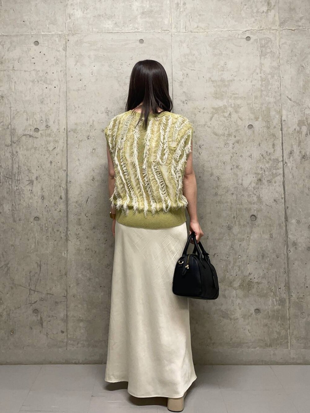 ホワイト系のサンダル、ホワイト系のスカート、イエロー系のニット/セーターを着用したレディースの夏コーディネートの5枚目の写真