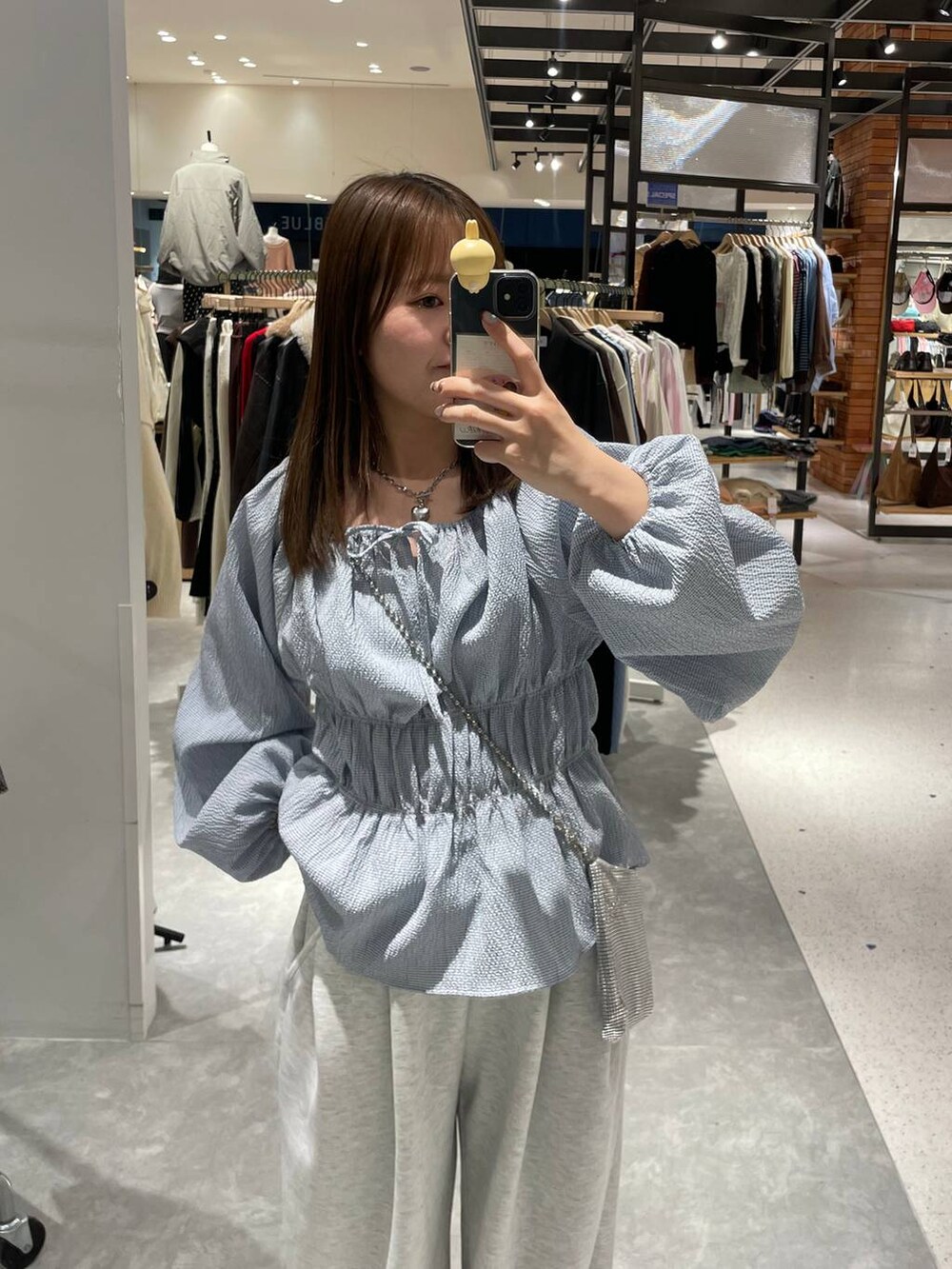 シルバー系のショルダーバッグ、グレー系のスウェットパンツ、ブルー系のTシャツ/カットソーを着用したレディースの冬コーディネートの4枚目の写真