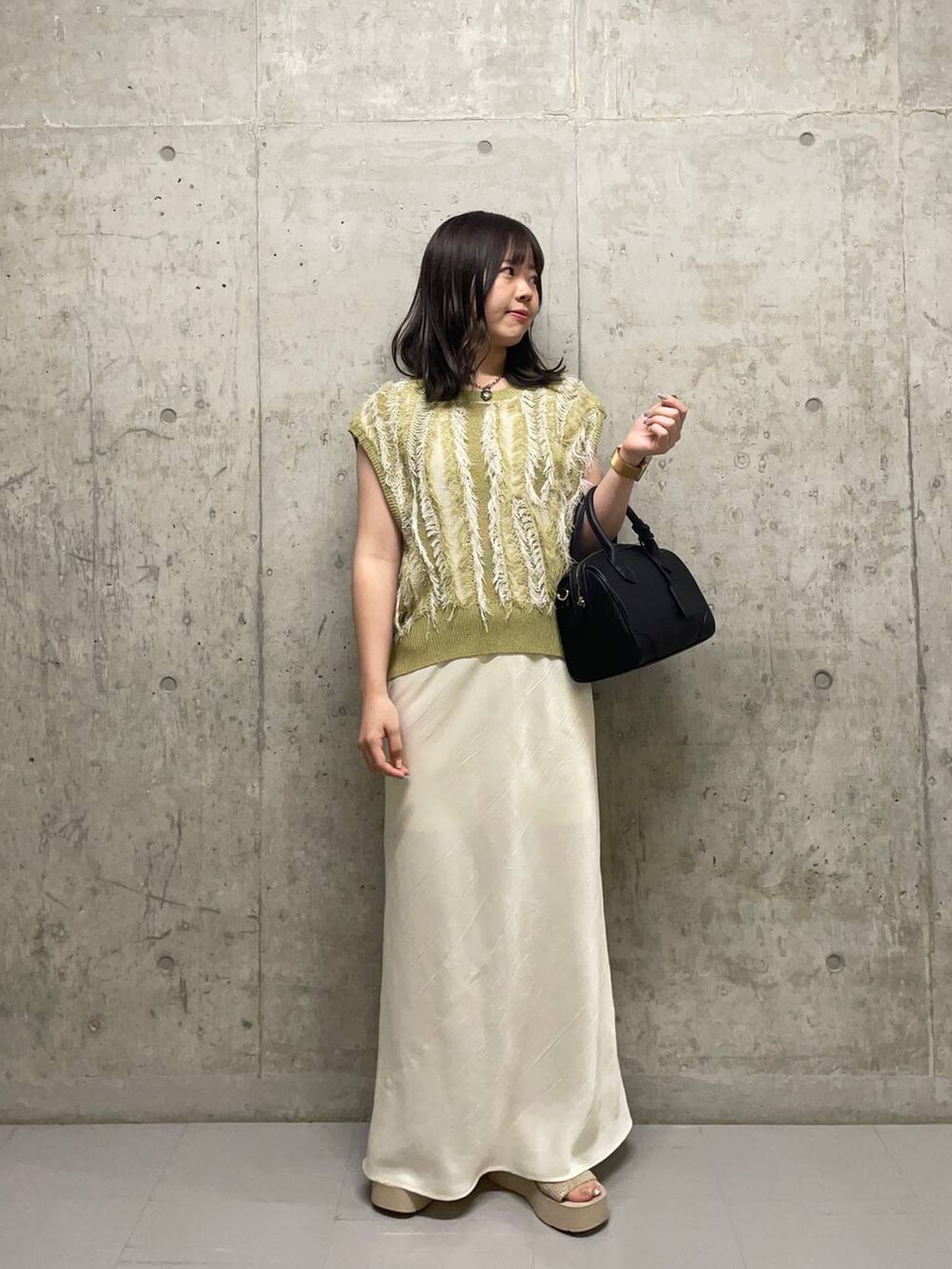 ホワイト系のサンダル、ホワイト系のスカート、イエロー系のニット/セーターを着用したレディースの夏コーディネートの4枚目の写真