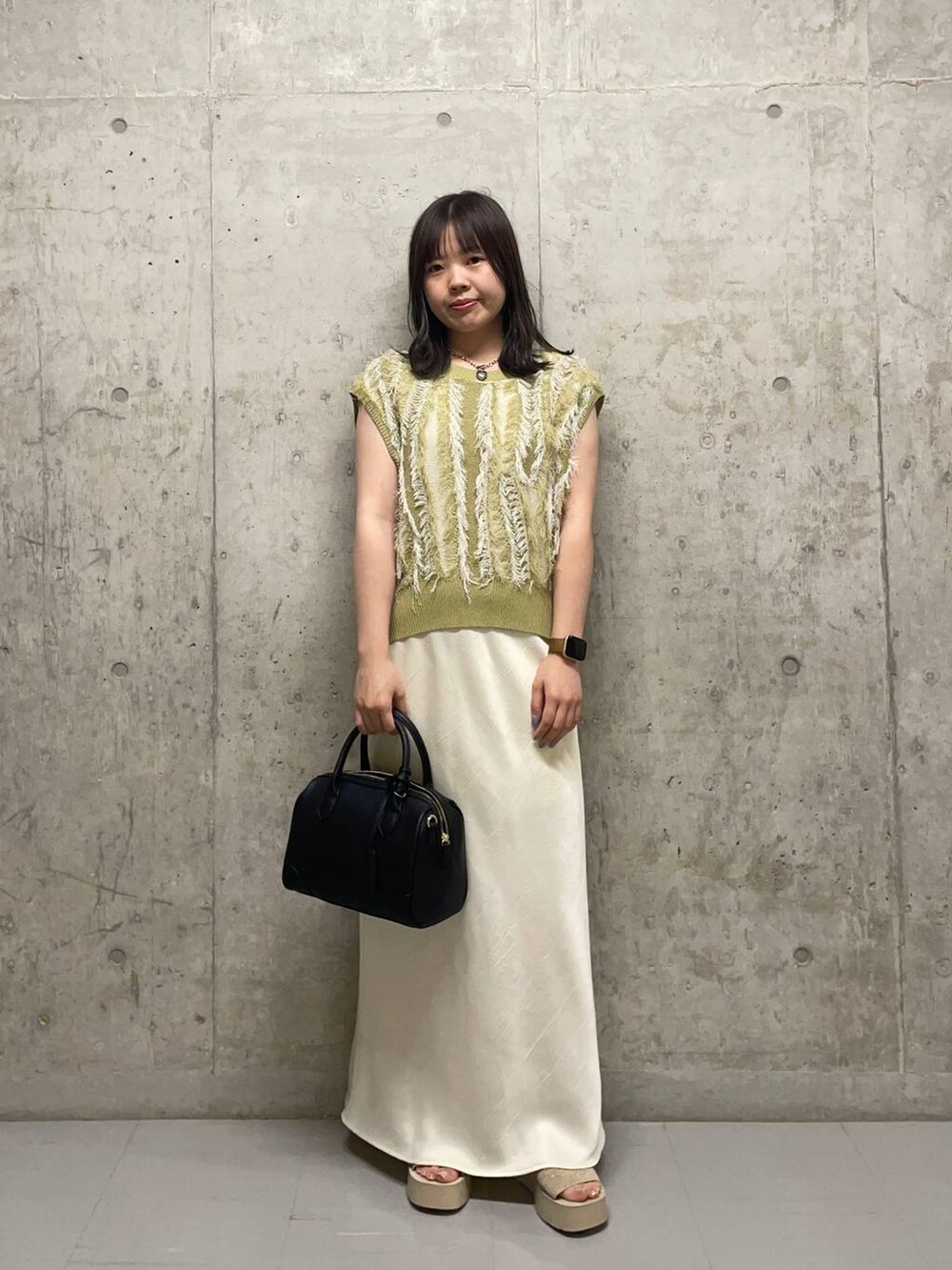 ホワイト系のサンダル、ホワイト系のスカート、イエロー系のニット/セーターを着用したレディースの夏コーディネートの2枚目の写真