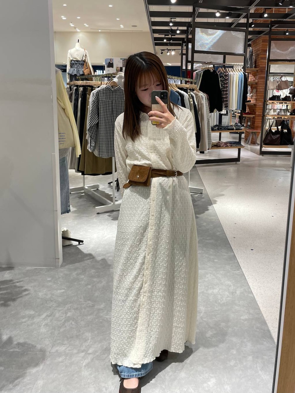 ブルー系のデニムパンツ、ブラウン系のスニーカー、ホワイト系のワンピースを着用したレディースの春コーディネートの4枚目の写真