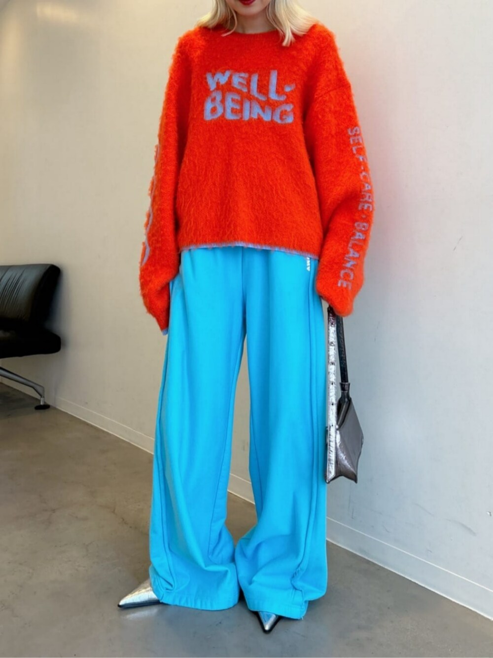 シルバー系のパンプス、シルバー系のショルダーバッグ、ブルー系のスウェットパンツを着用したレディースの秋コーディネートの3枚目の写真