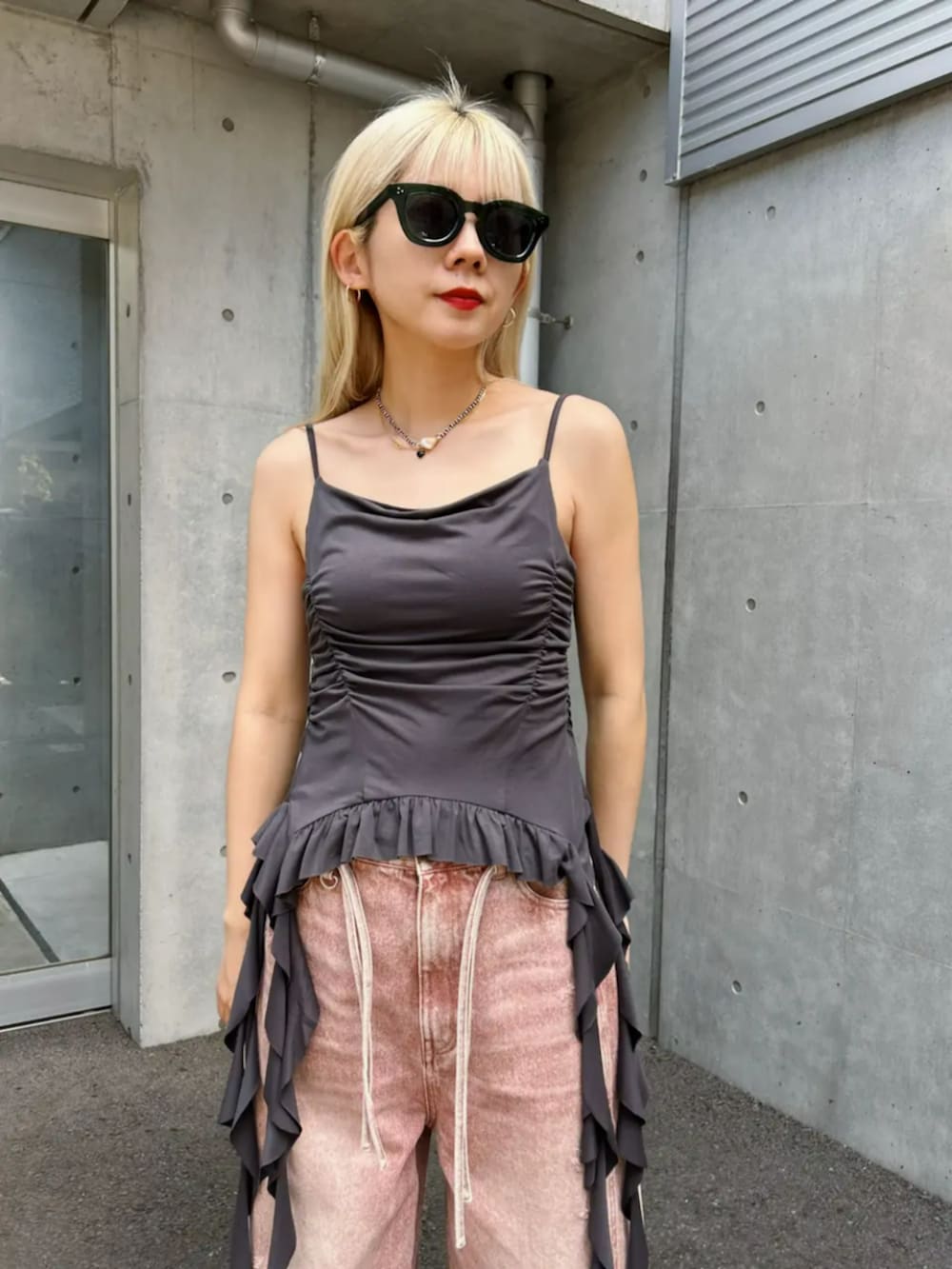 ブラック系のパンプス、ピンク系のデニムパンツ、グレー系のキャミソールを着用したレディースの春コーディネートの2枚目の写真