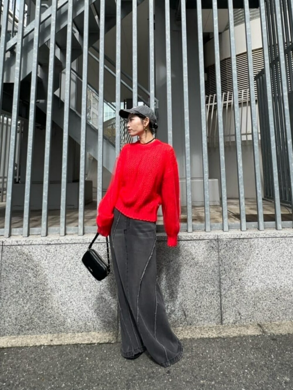 ブラック系のショルダーバッグ、ブラック系のデニムスカート、レッド系のニット/セーターを着用したレディースの秋コーディネートの2枚目の写真