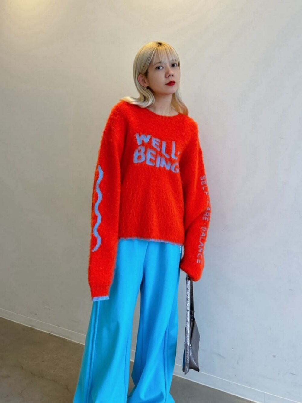 シルバー系のパンプス、シルバー系のショルダーバッグ、ブルー系のスウェットパンツを着用したレディースの秋コーディネートの2枚目の写真